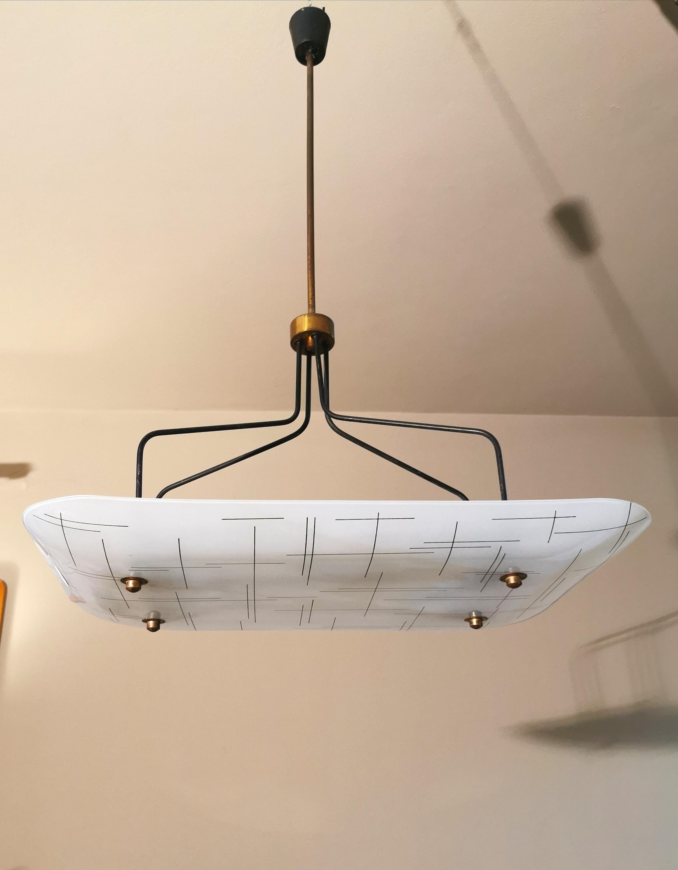 Particular mid-century chandelier by the unknown designer with 4-light brass structure that supports a large white rectangular glass with striped designs. Made in Italy in the 1960s.