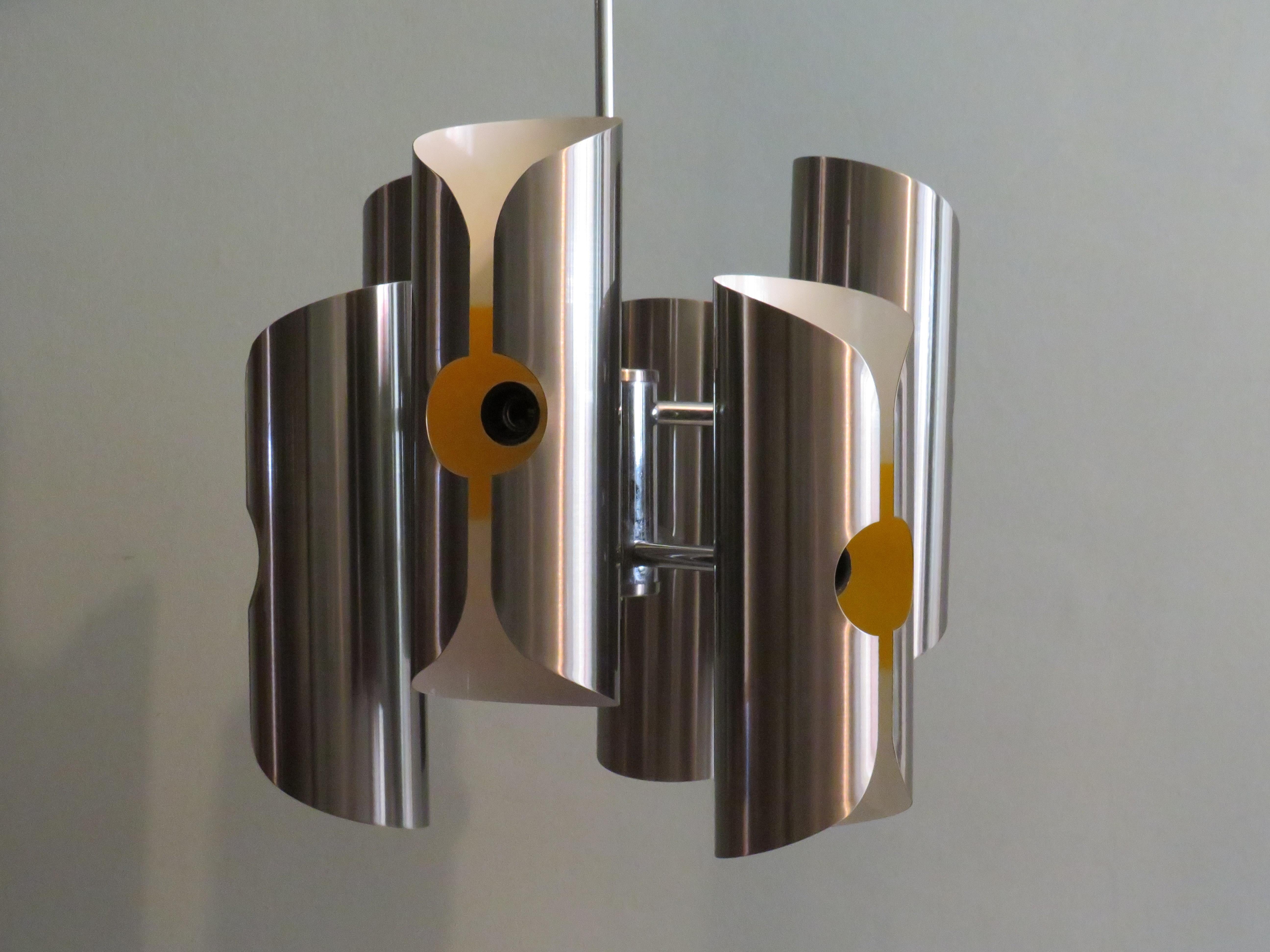 Chandelier with chrome frame and 6 pleated sleeves in brushed stainless steel with a partial yellow interior.
The chandelier is in good vintage condition and is complete with hanging system and ceiling cap.
The maximum height with hanging system