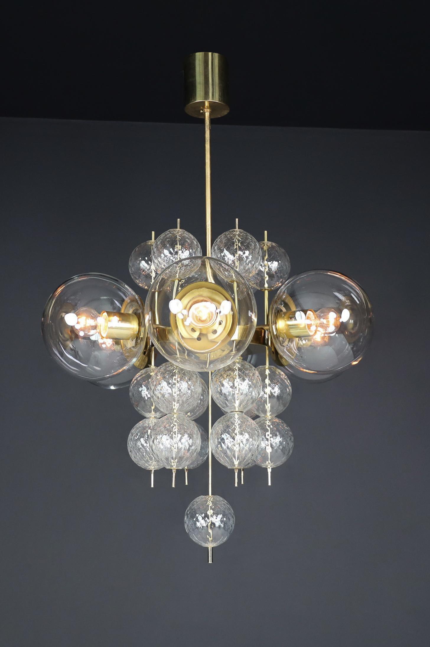 Mid-Century Chandelier with Brass Fixture and  Glass Globes by Preciosa, Czechia, 1960

This stunning Mid-Century chandelier features a brass fixture designed and produced by the renowned Preciosa Factory in Czechia. It includes six large hand-blown