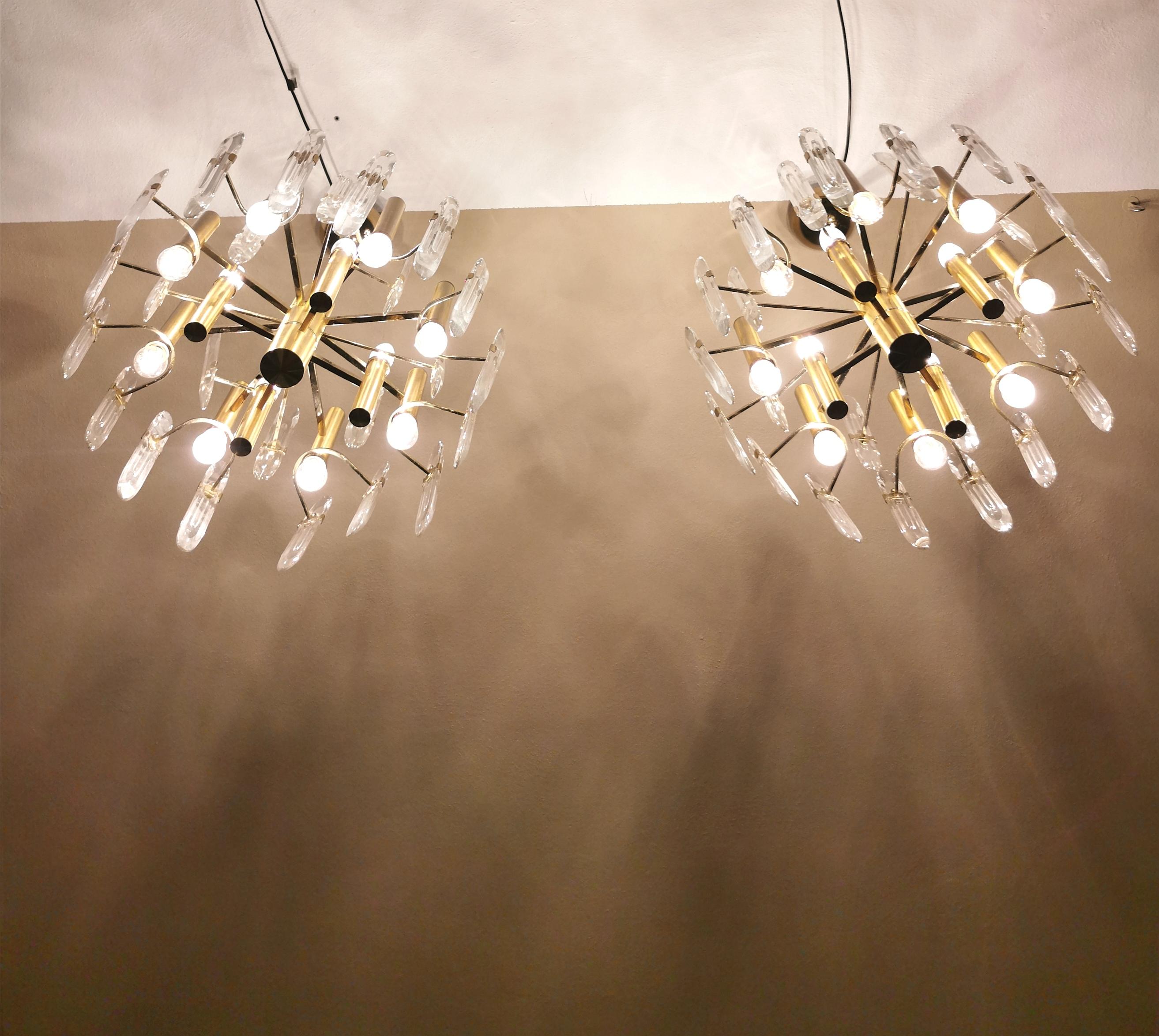 Set of 2 chandeliers designed by the Italian designer Gaetano Sciolari. each single chandelier has 4 lights in the upper part and 8 E27 lights in the lower part, with a brass and golden aluminum structure supporting 16 ellipse-shaped beveled crystal