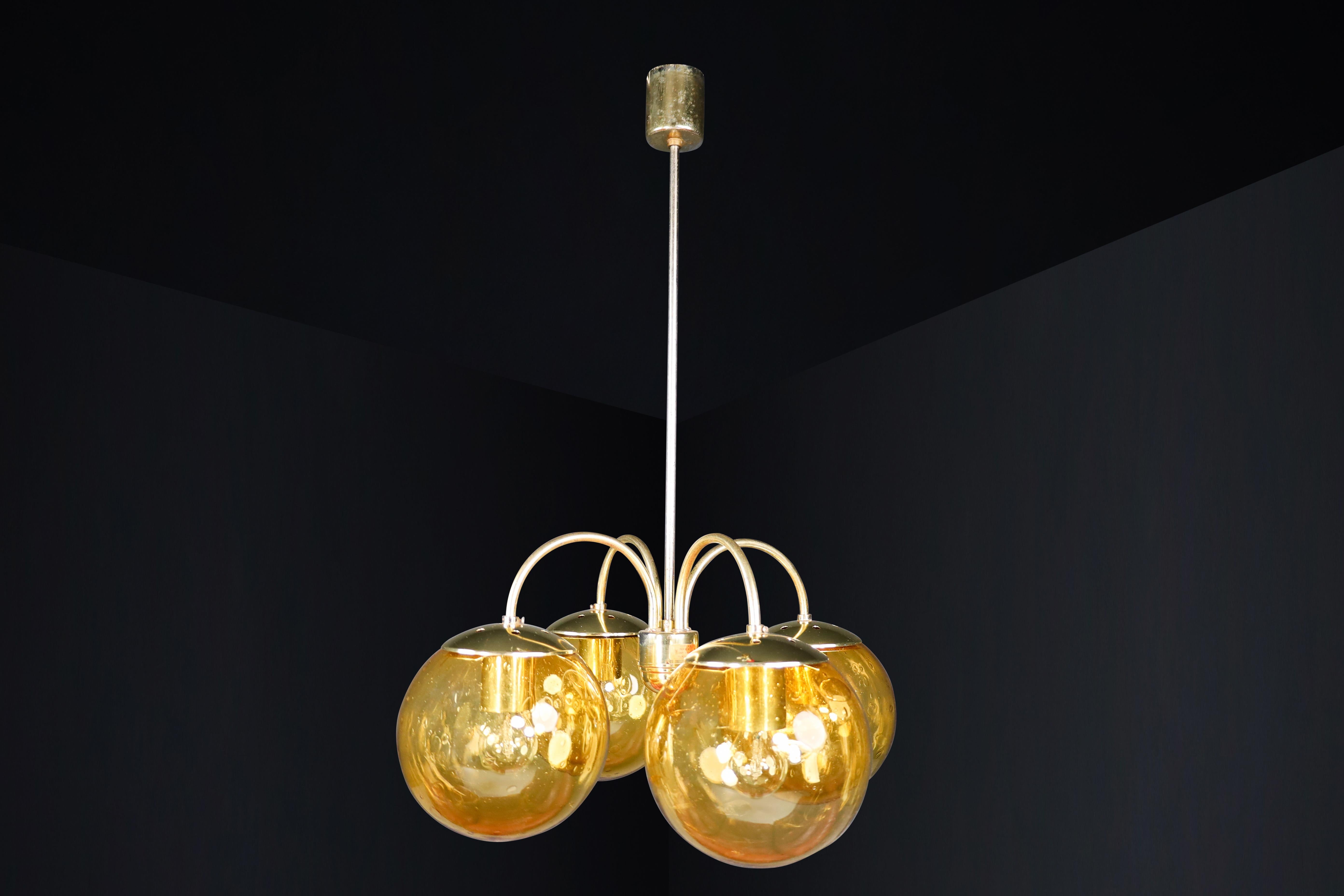 Midcentury Chandeliers in Brass and amber-colored glass Czech Republic 1960s.

We have two refined chandeliers available for purchase. They have a structured design with four spherical amber-colored glass shades attached to a brass frame. The