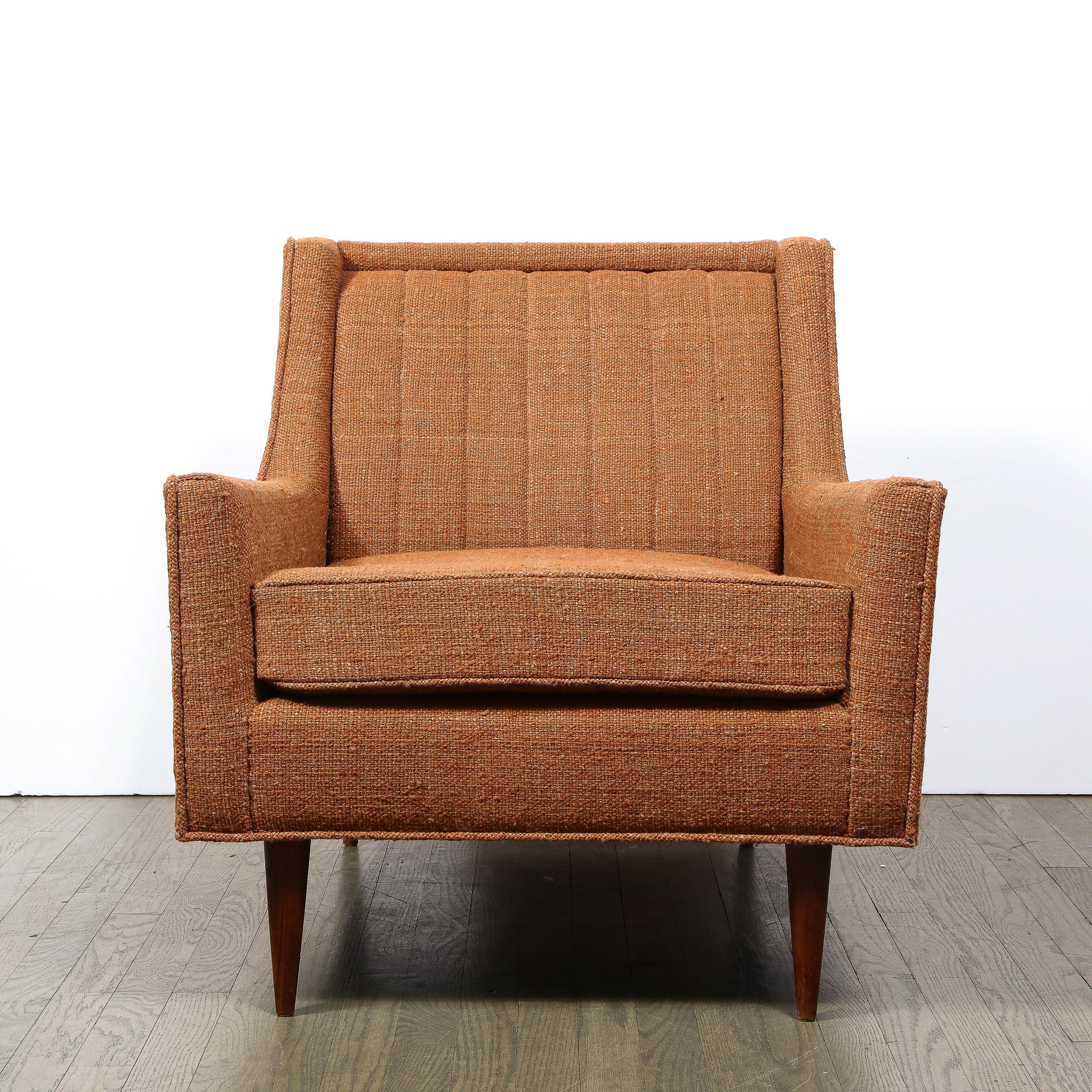 This refined Mid-Century Modern arm chair was realized in the United States circa 1950. Sitting on conical legs, this piece offers a wealth of beautiful details including channel detailing on its subtly shadowboxed back and clean geometric angles