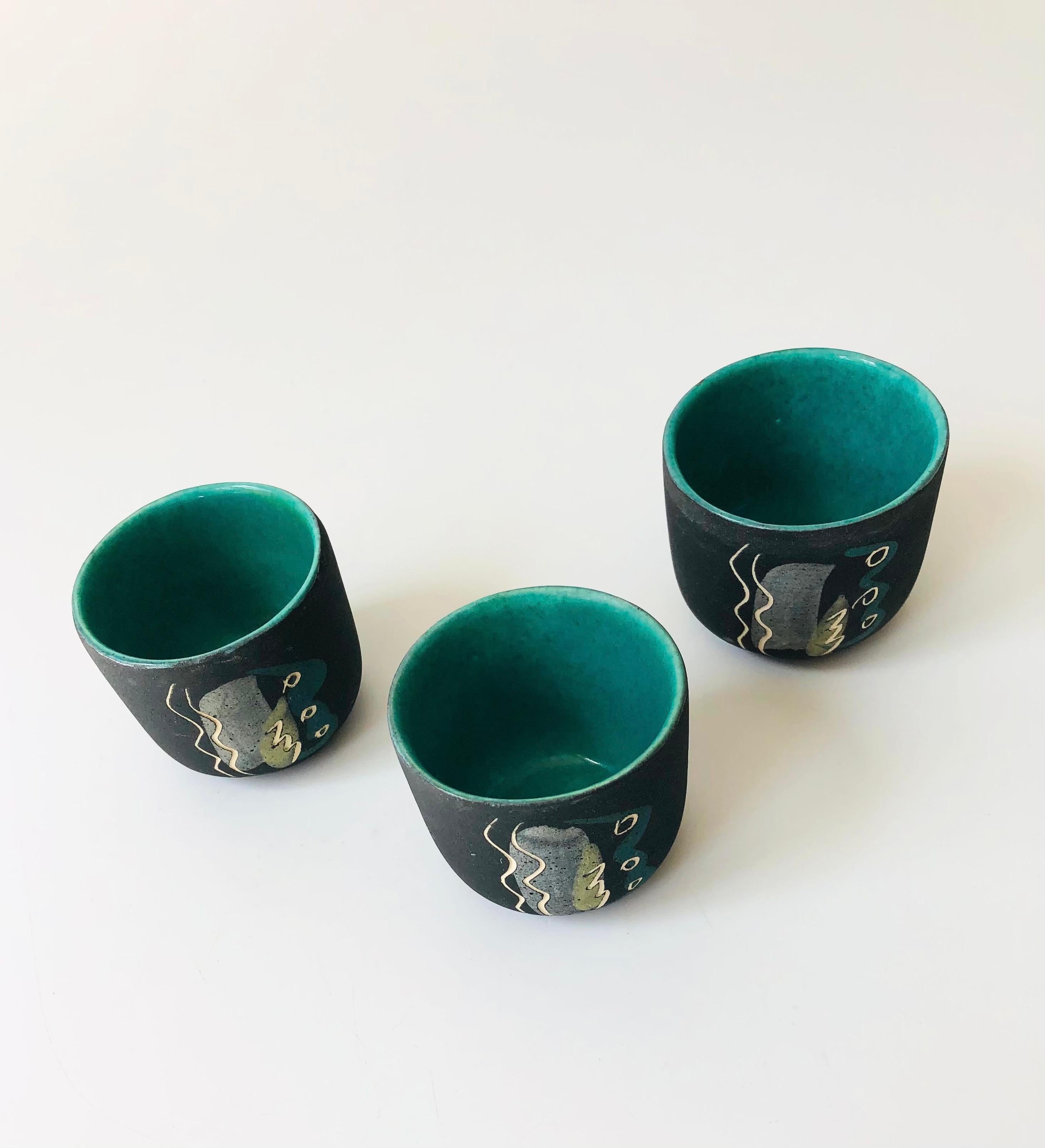 A set of 3 mid century studio teacups from the 1940s-50s by husband and wife ceramicists, Charles and Alice Smith of California. Great abstract design on the fronts consisting of carved lines and overlapping glazes. Finished in black matte glazes