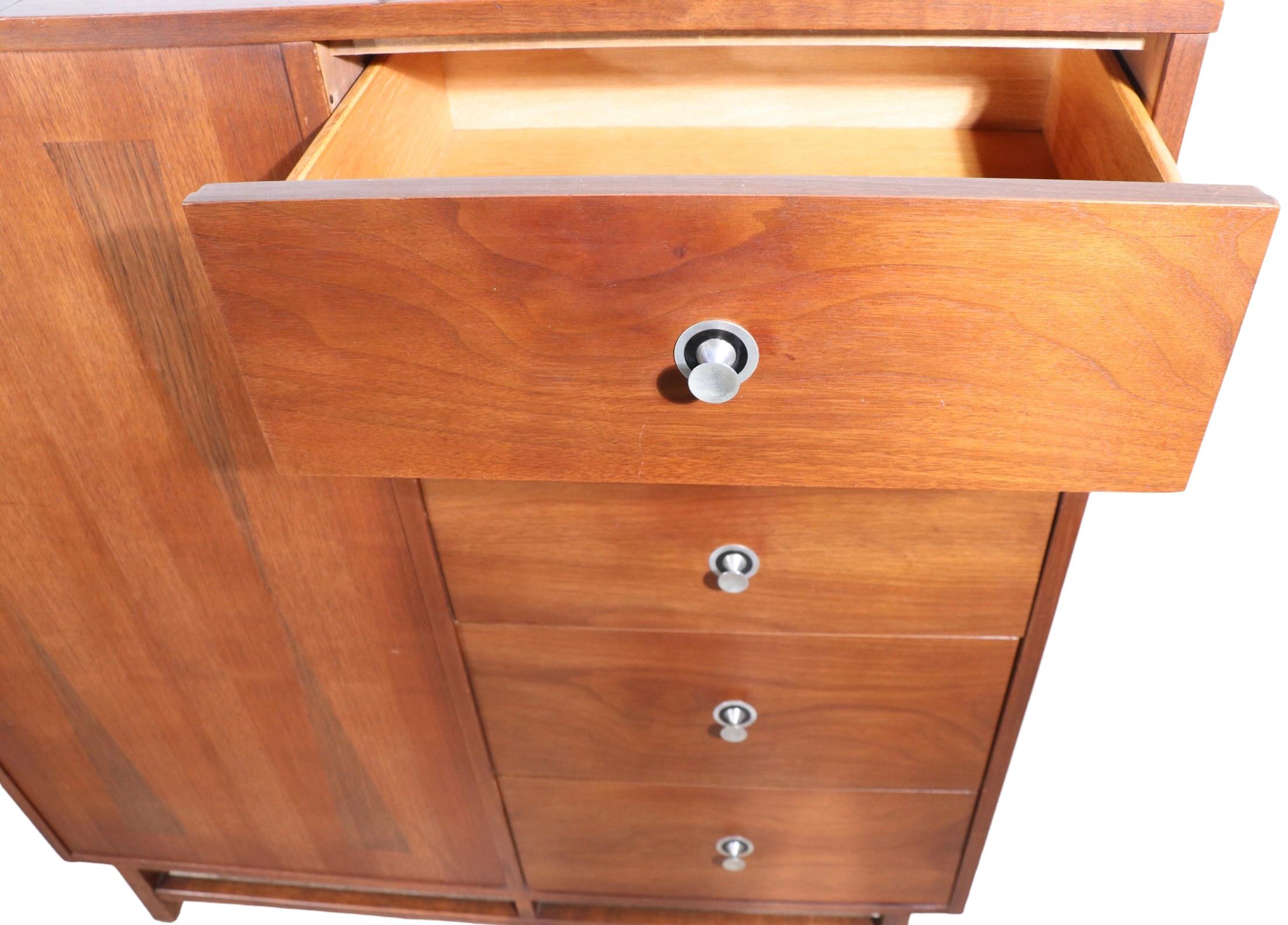 Exceptional mid century wardrobe by noted American furniture maker, marked Distinctive Furniture by Stanley.
The chest features an unusual wardrobe section which opens from the side, flanked by a bank of five deep drawers, providing ample storage