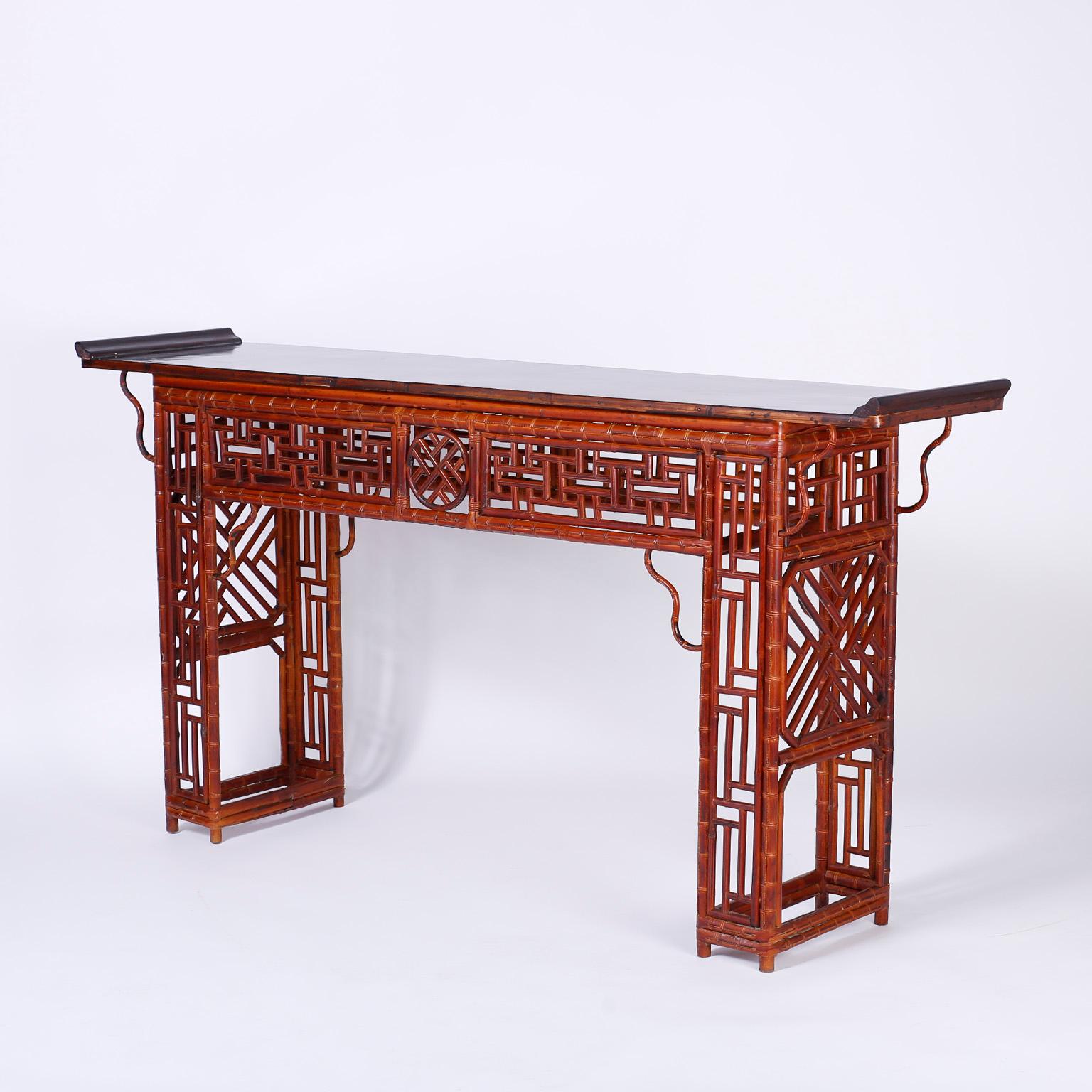 Refined Chinese Chippendale style console with a black lacquer top over a bamboo frame having Chippendale designs tastefully applied to the entire composition including a center medallion, brackets, and eight decorated legs.