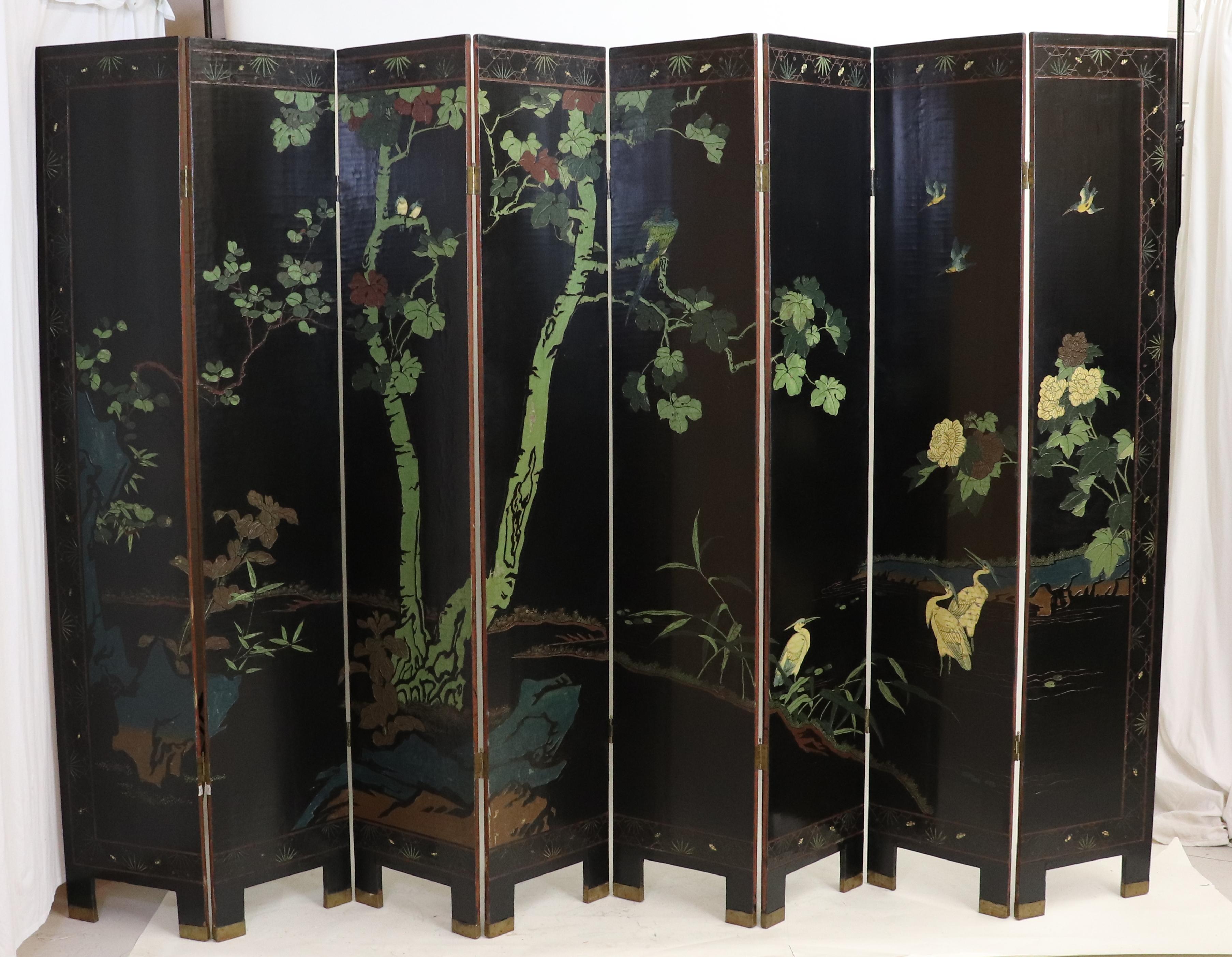 Ce paravent double face à huit panneaux en laque noire d'exportation Coromandel représente un paysage naturel avec des oiseaux, des arbres et des chrysanthèmes. Dans la technique de la laque de Coromandel, une couche de quelques millimètres