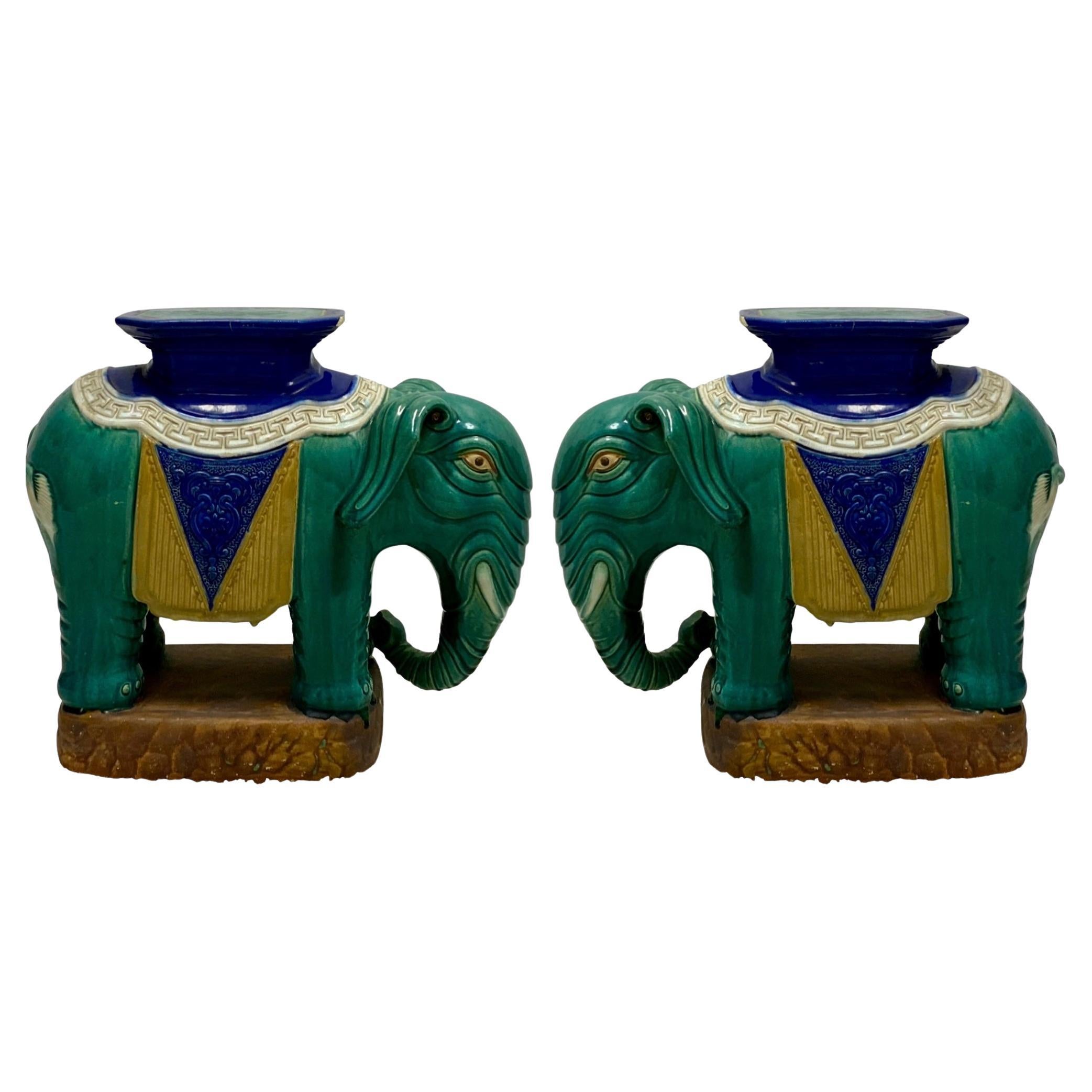 This is a pair of mid-century Chinese Export style elephant form garden seats or side tables. They have a vibrant majolica glaze in blue, green and gold and are ceramic/ pottery. They are in very good condition with age appropriate wear.