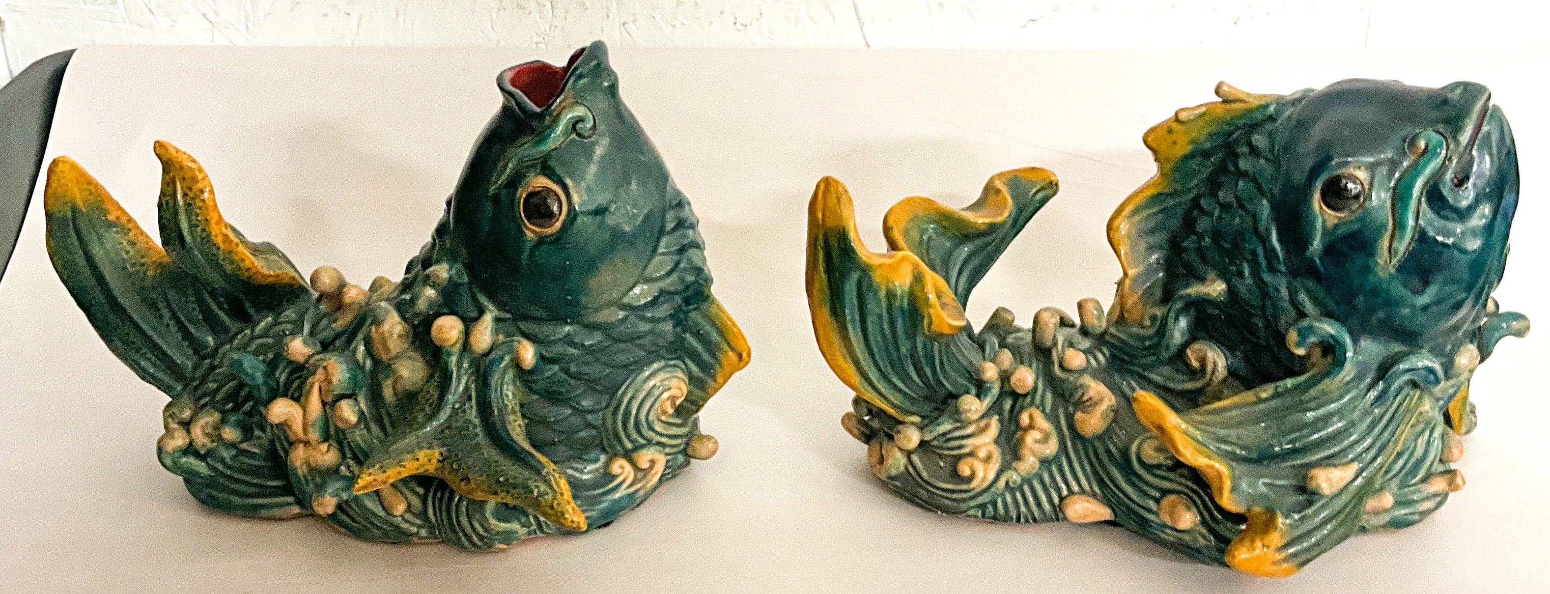 This is a pair of Chinese Export style decorative terracotta fish. They are a deep blue-green paint with gold accents. The are hand painted and in very good condition.