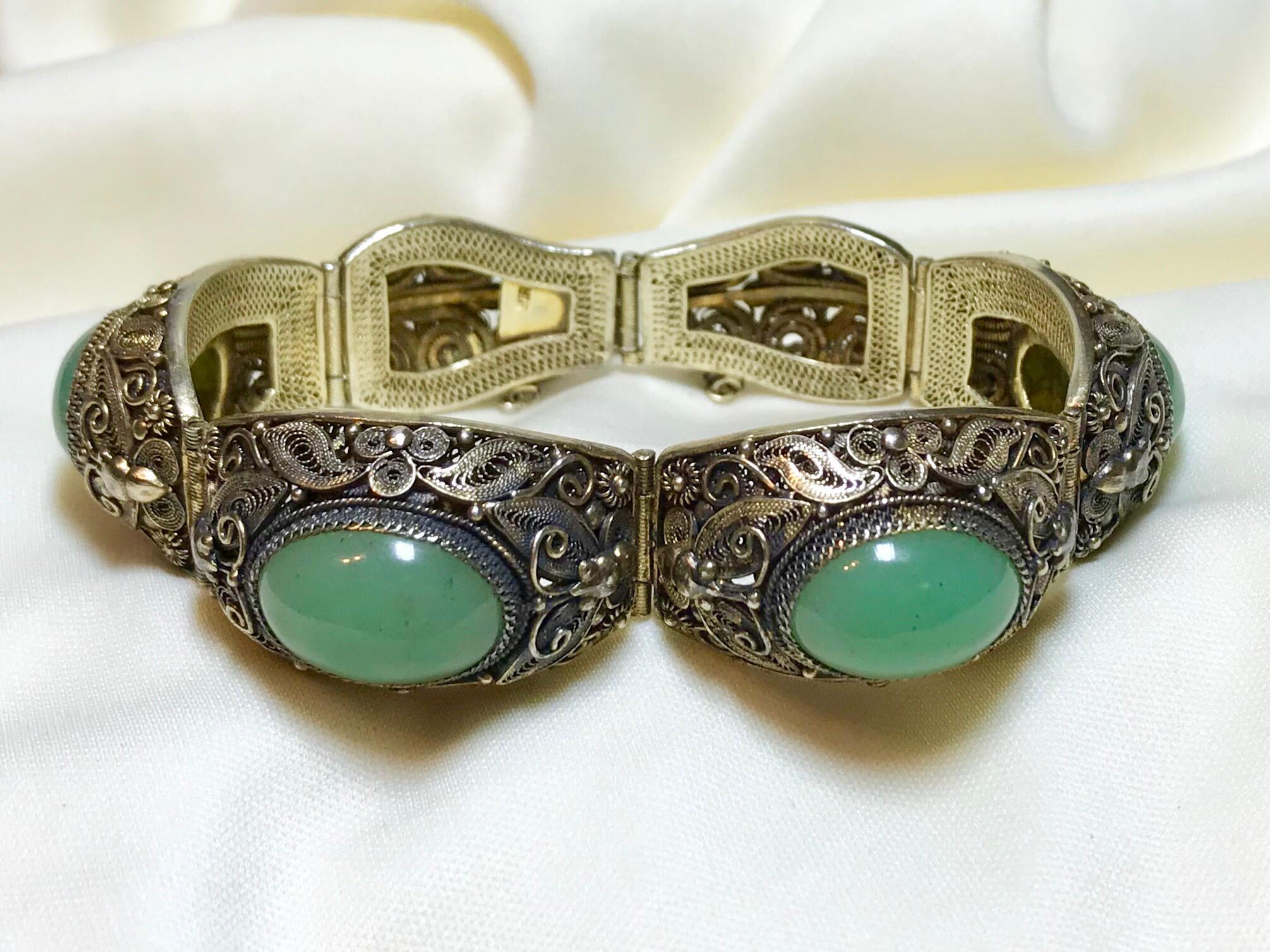 Circa 1940s to 1950s ornate gold-plated sterling silver bracelet with beautiful filigree detail and embellished with moth motifs, typical in Chinese jewelry.. It is bezel set with oval jade cabochons and measures 7.5