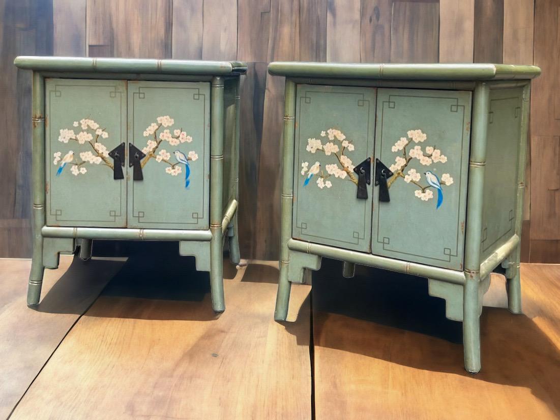 This is a pair of mid-century hand painted Aesthetic Movement inspired celadon bamboo cabinets. They have bird and floral fronts with pinstripe details. They open to single shelf. They are unmarked and have general age wear.