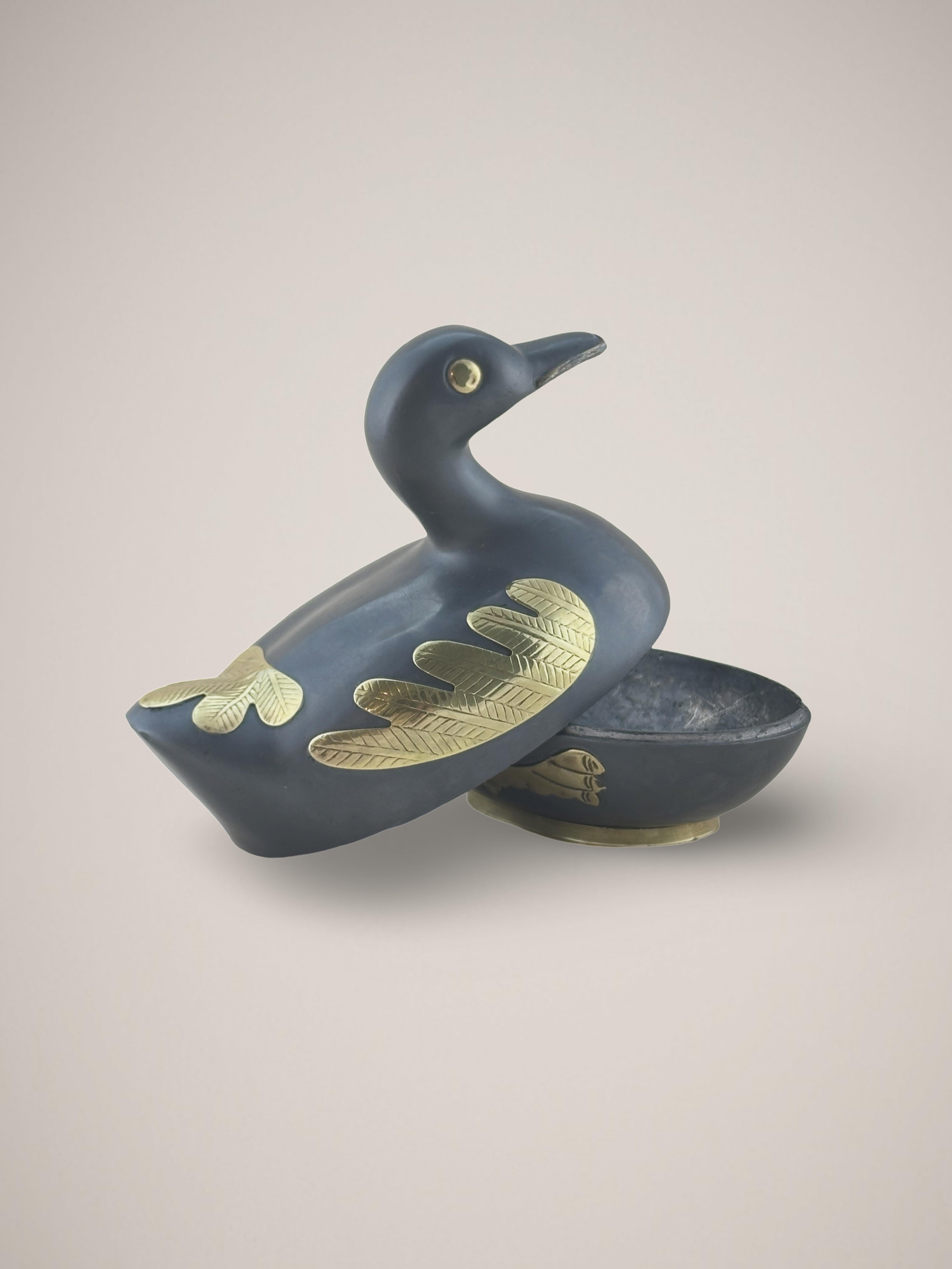 A pewter and brass trinket box made in Hong Kong during the mid-20th century. 


An iconic and utilitarian duck-shaped box that represents prosperity and fortune. The duck's body is cast in dark pewter metal, with thin, intricate overlays of