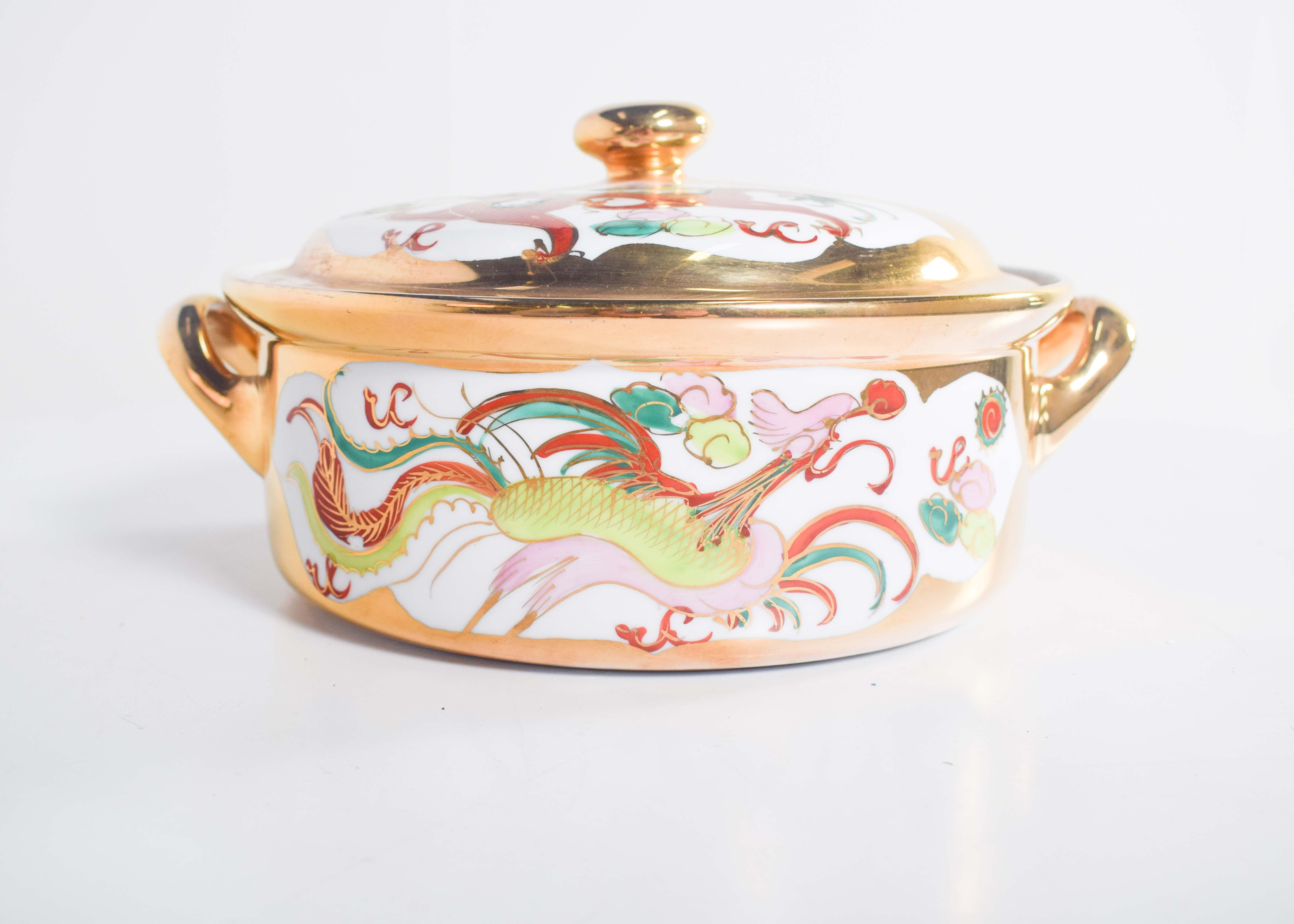 Ce pot exquis en porcelaine chinoise est doté de deux poignées élégamment incurvées et d'un couvercle arrondi, dégageant une impression de luxe et d'art traditionnel. La surface est richement décorée d'une combinaison de motifs dorés et polychromes,