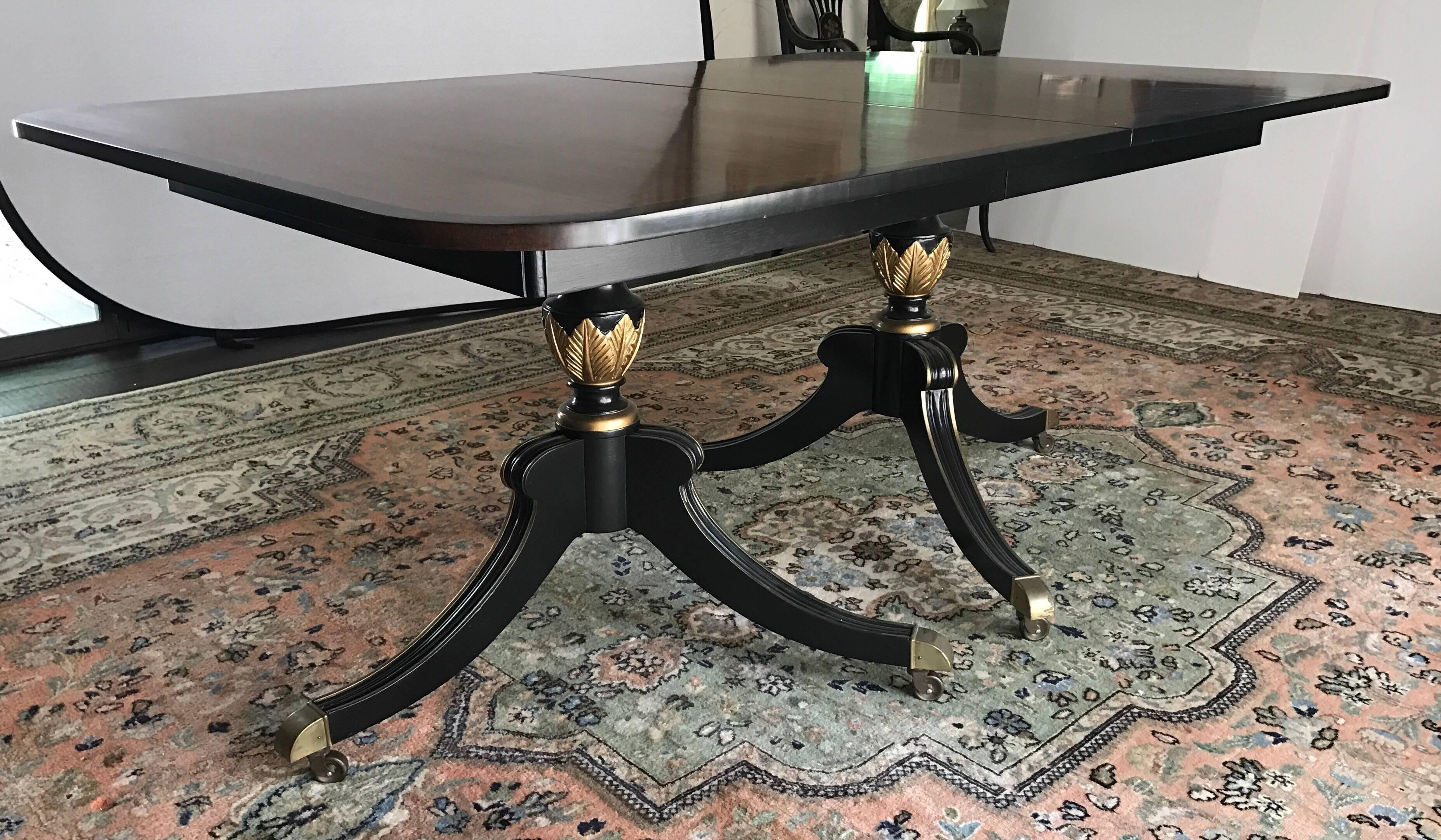 Elegant chinoiserie black and gold dining set has a double pedestal table with gold acanthus leaf detail and brass feet on casters. Two armchairs and four side chairs have exquisite painted gold detail and turquoise velvet seats. Table has three 12