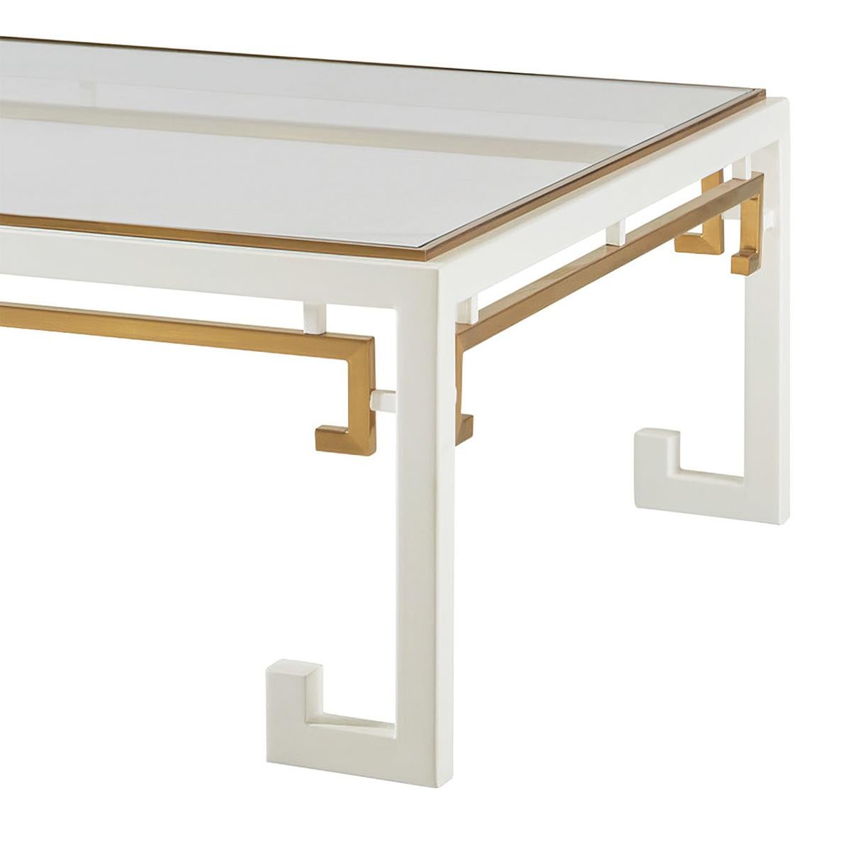 This midcentury chinoiserie cocktail table is an exquisite blend of Classic Asian and modern midcentury style. With its striking white paint, brass metal accents, and clear glass top, it is a perfect example of functional art that will add a touch