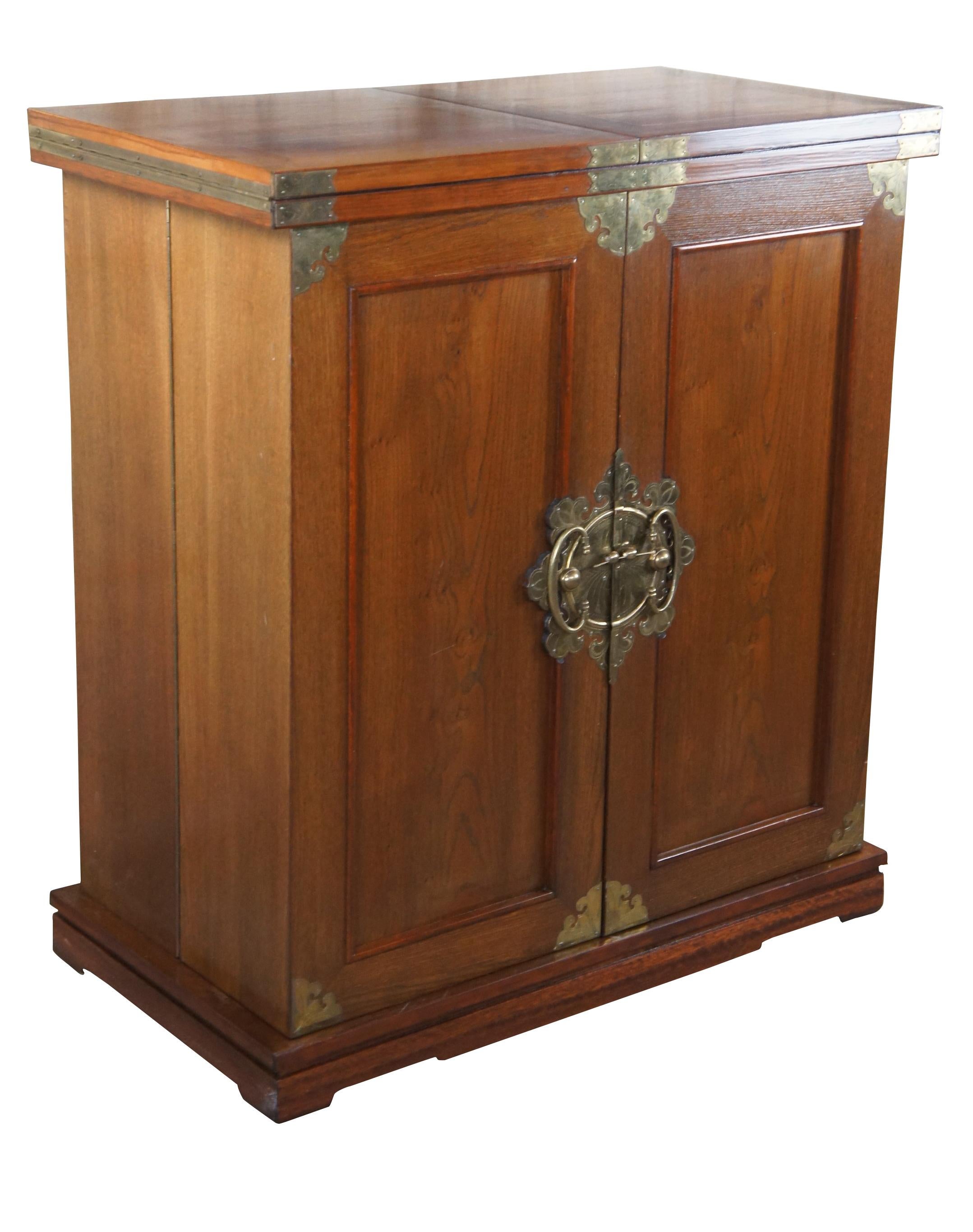 An impressive mid 20th century Asian expandable dry bar or server. Made from elm with beautiful brass mounts. Opens to a large serving surface with inlaid calligraphy and Greek key. Lower cabinet features storage for wine or liquor, hanging