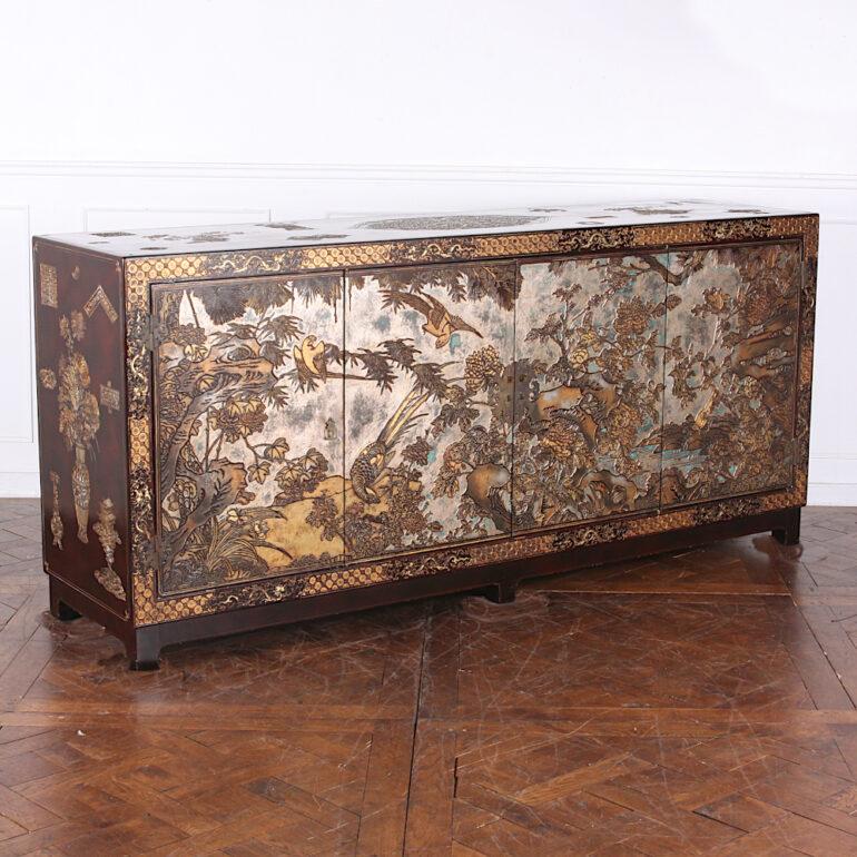 A stunning Asian or ‘Chinoiserie’ mid-20th century lacquer sideboard featuring carved coromandel lacquer landscape scenes to the front and a variety of decorative flowers, fans etc over the rest of the piece. Contrasting carved ‘honeycomb’ motif