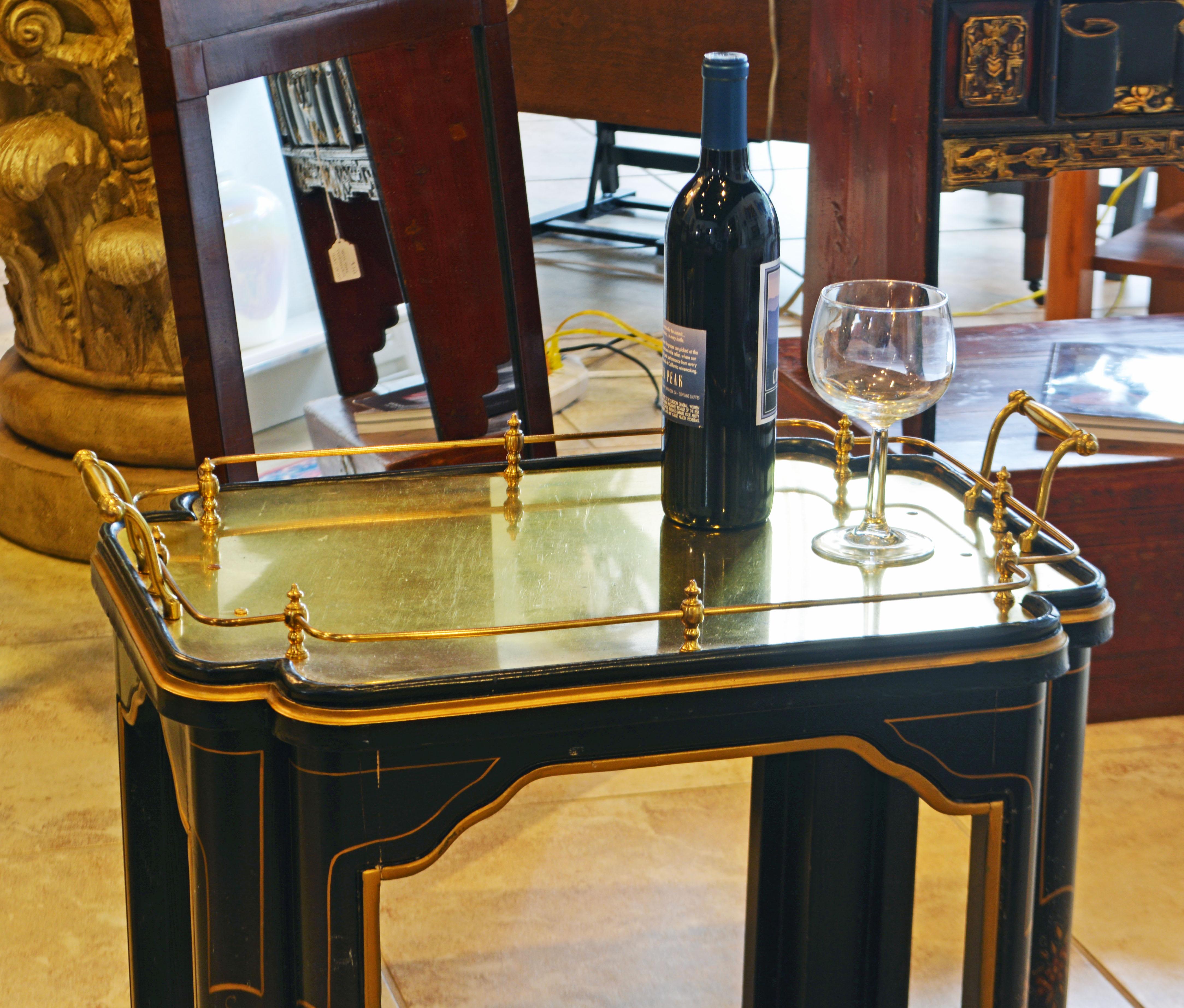 This elegant scaloped design accent table features a top in the shape of a solid brass tray with handles and gallery attached to a black and gllt lacquerred frame in the chinoiserie chippendale style. Note the floral decorated double legs.