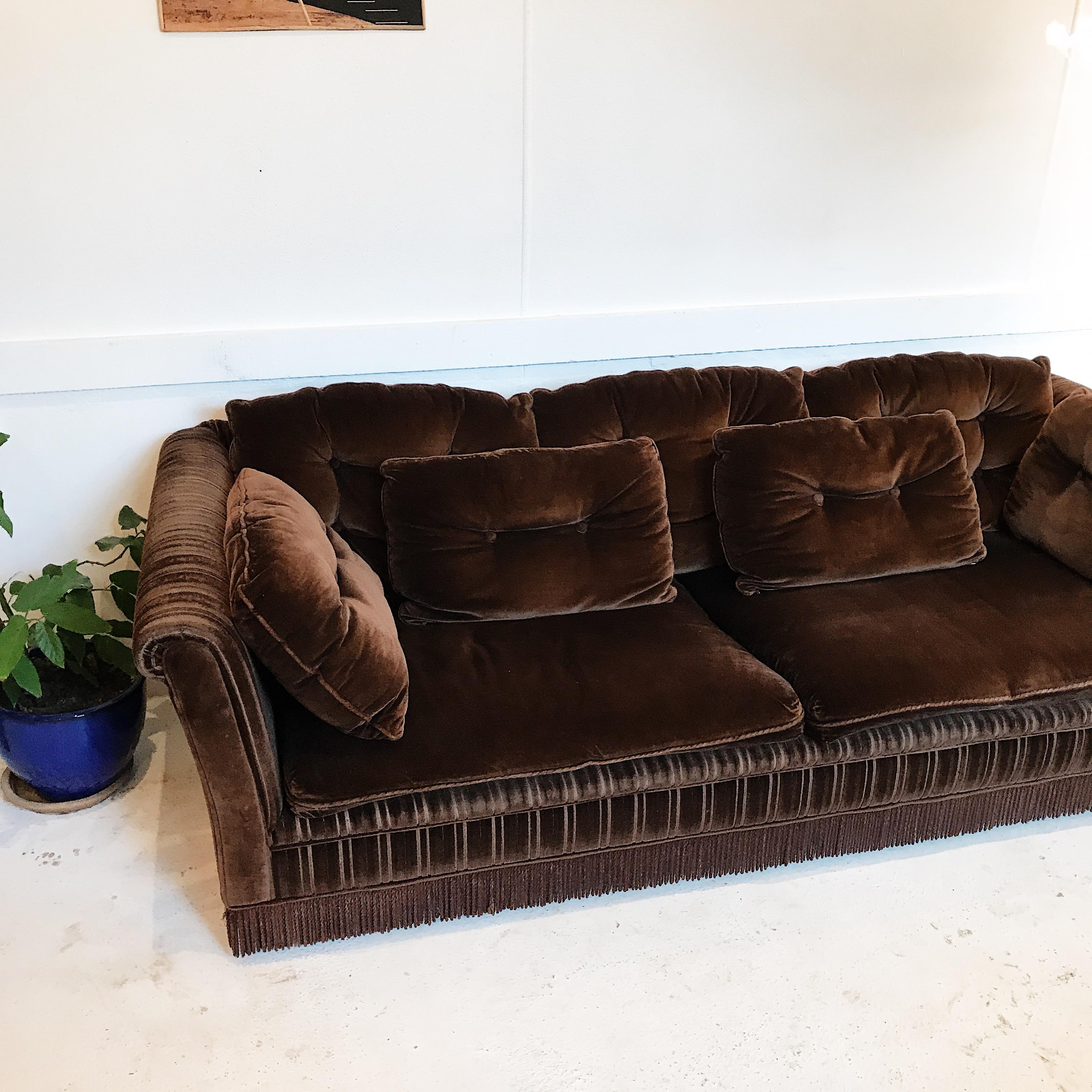 Absolutely immaculate chocolate brown velvet three-seat sofa with an abundance of buttoned pillows, cord striped arms and tasseled at the base.

 