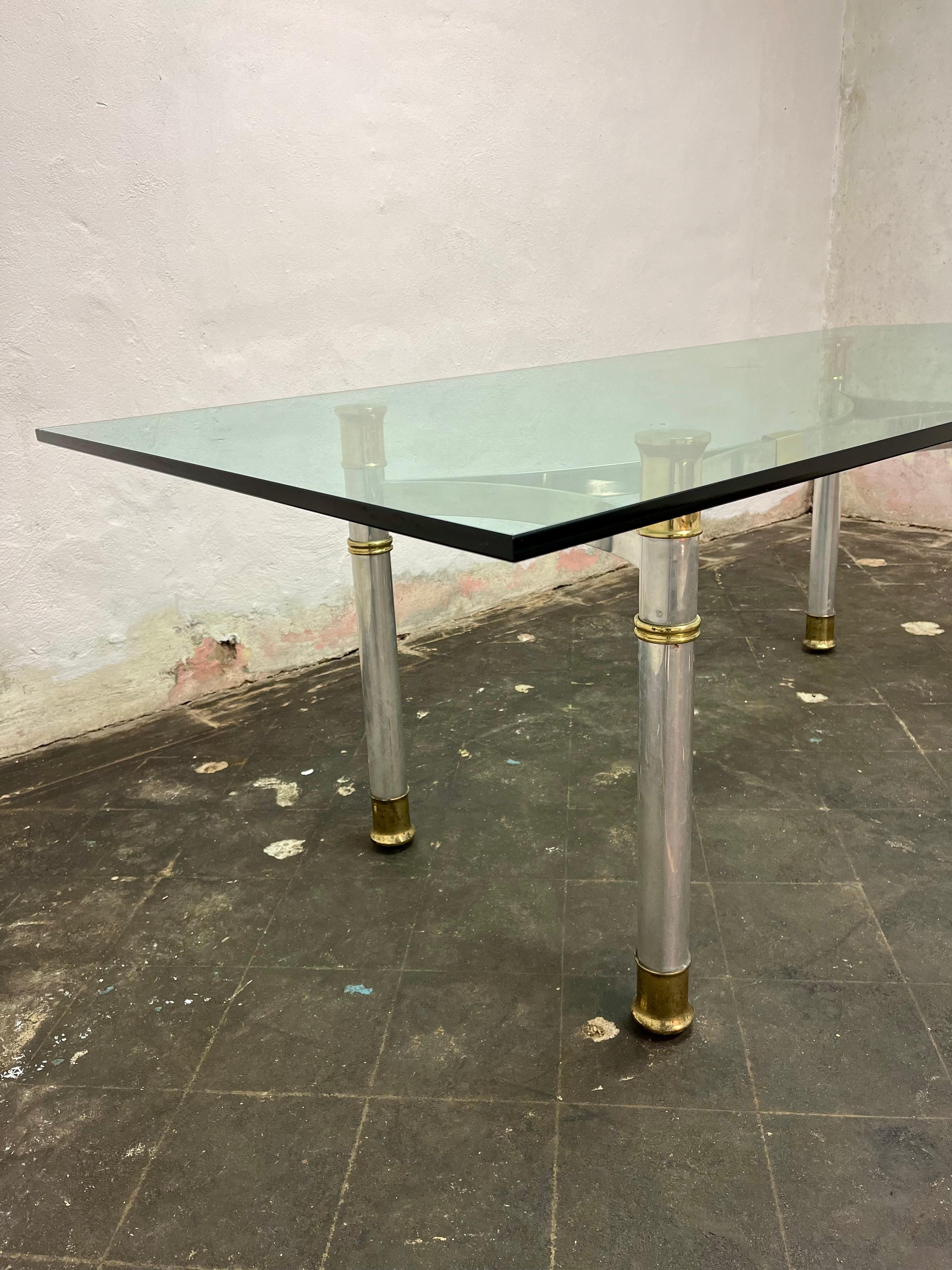 Beautiful chrome and brass glass top dining table. Thick columnar legs with brass capped feet and supports. X base stretcher across the top of base offset with center brass wrap. Elegant and sophisticated. Heavy 3/4