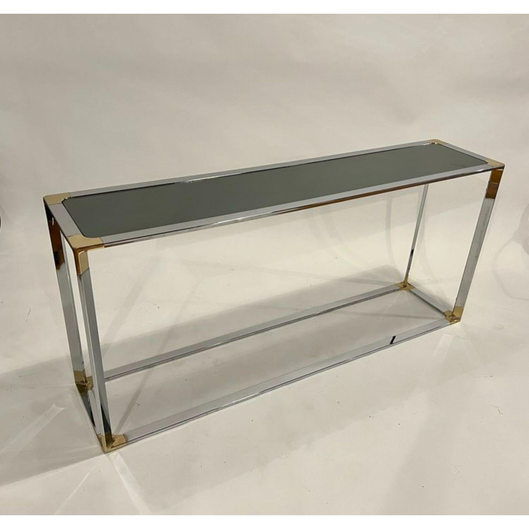 1970's chrome console or sofa table with brass accents and a smoky mirror top.

Additional Information:
Materials: Chrome, Brass accents, Mirror
Style: Mid-Century Modern, Minimalist, Modern
Table Shape: Rectangle
Styled After: Milo Baughman Romeo