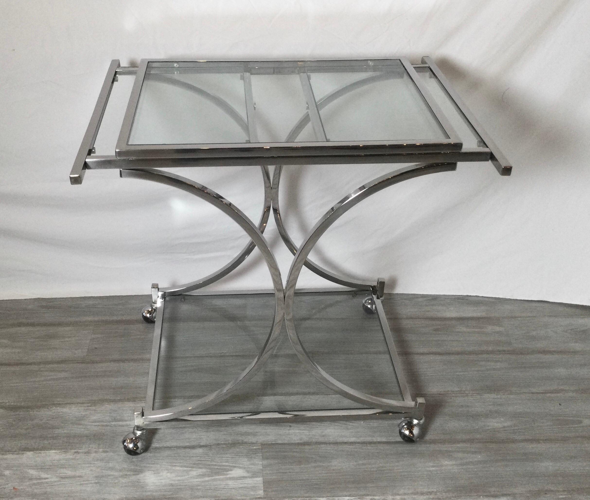 A chic chrome and glass bar or dessert cart with expandable sides. The top tier with leafs that pull out for extra working surface. Measures: 31.5 closed, opens to 51 inches.