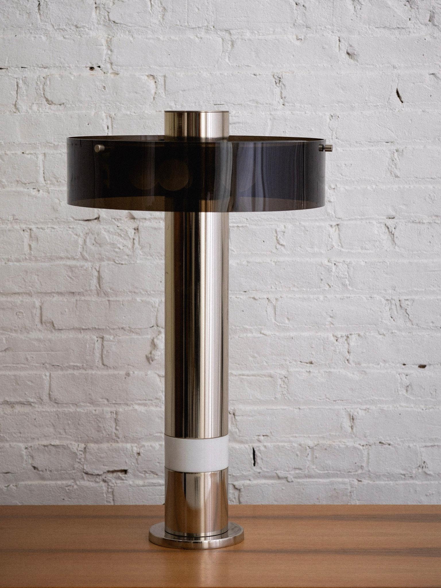 A midcentury chrome and acrylic table lamp. Chrome cylinder features a lower internal light and upper six bulb sockets covered with a smoke acrylic shade. Lower light source can be turned on with or without upper lighting.