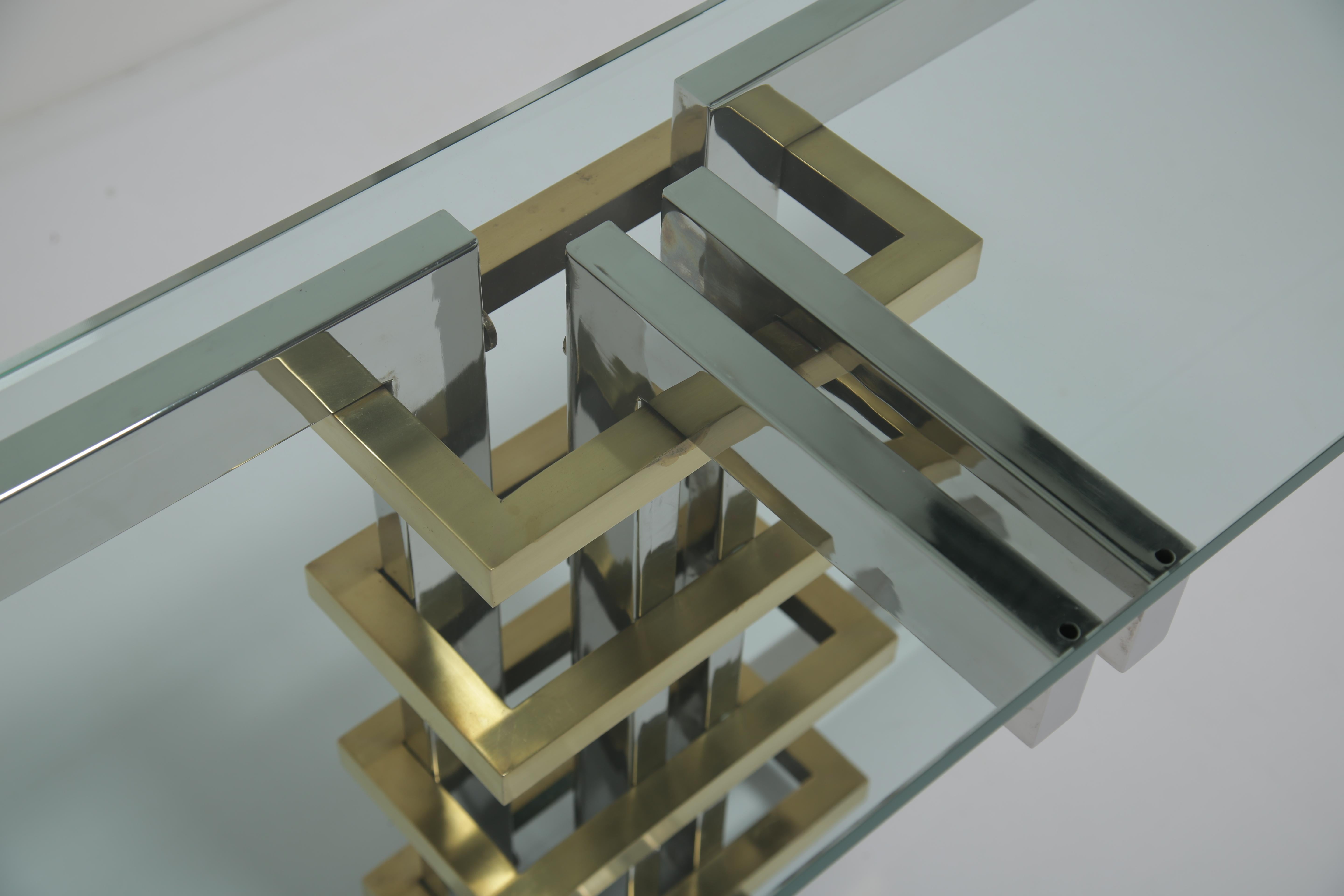 Extremely Sculptural console table designed by Alfredo Freda for Cittone Oggi. We currently have a pair of these tables but this listing is for one. Chrome and brass with a thick glass top. This is a very striking piece of furniture that is