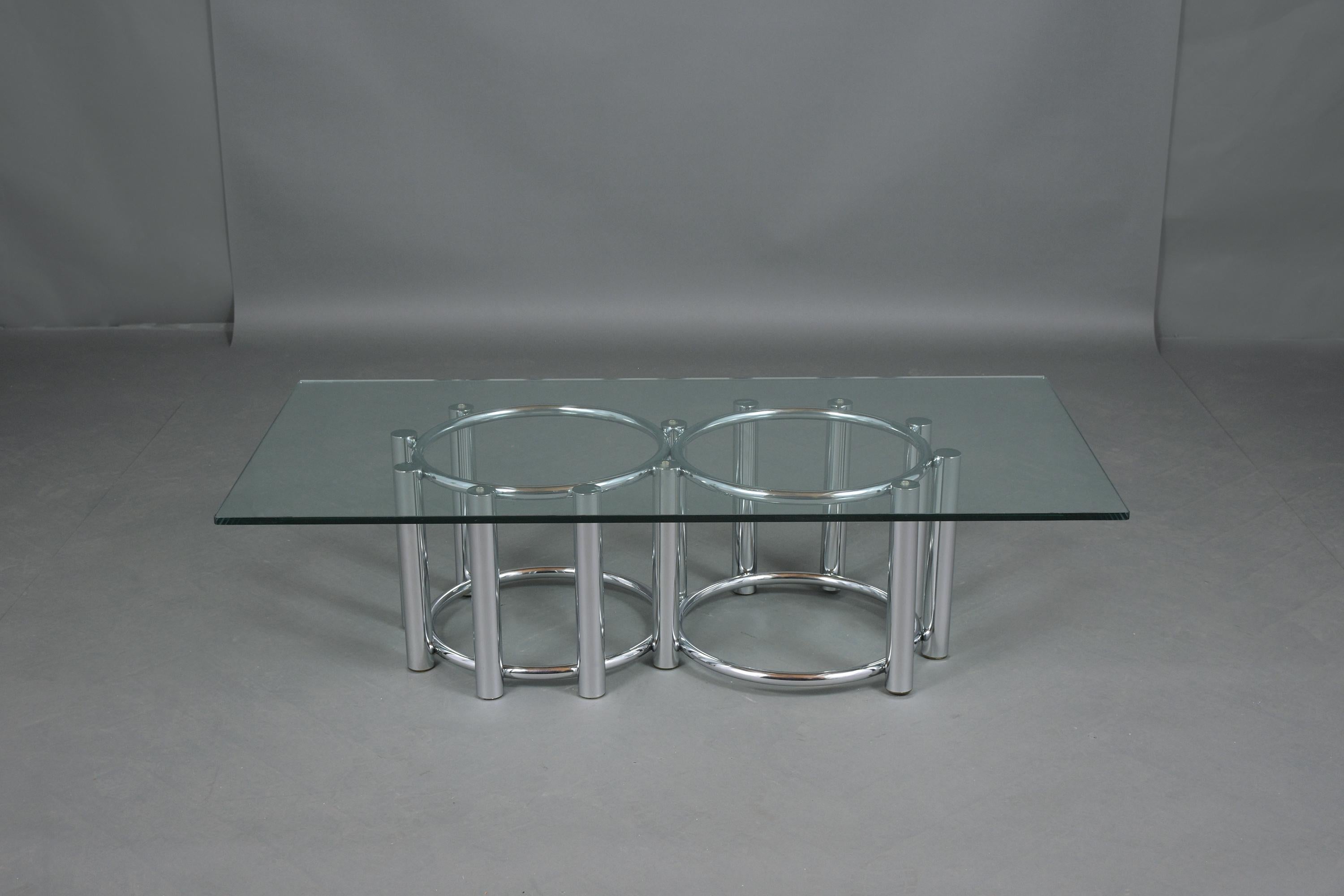 An extraordinary 1960s mid-century coffee table crafted out of steel with a chrome finish in great condition and has been professionally restored by our team of expert craftsmen. This piece features a new tempered clear glass top supported by a