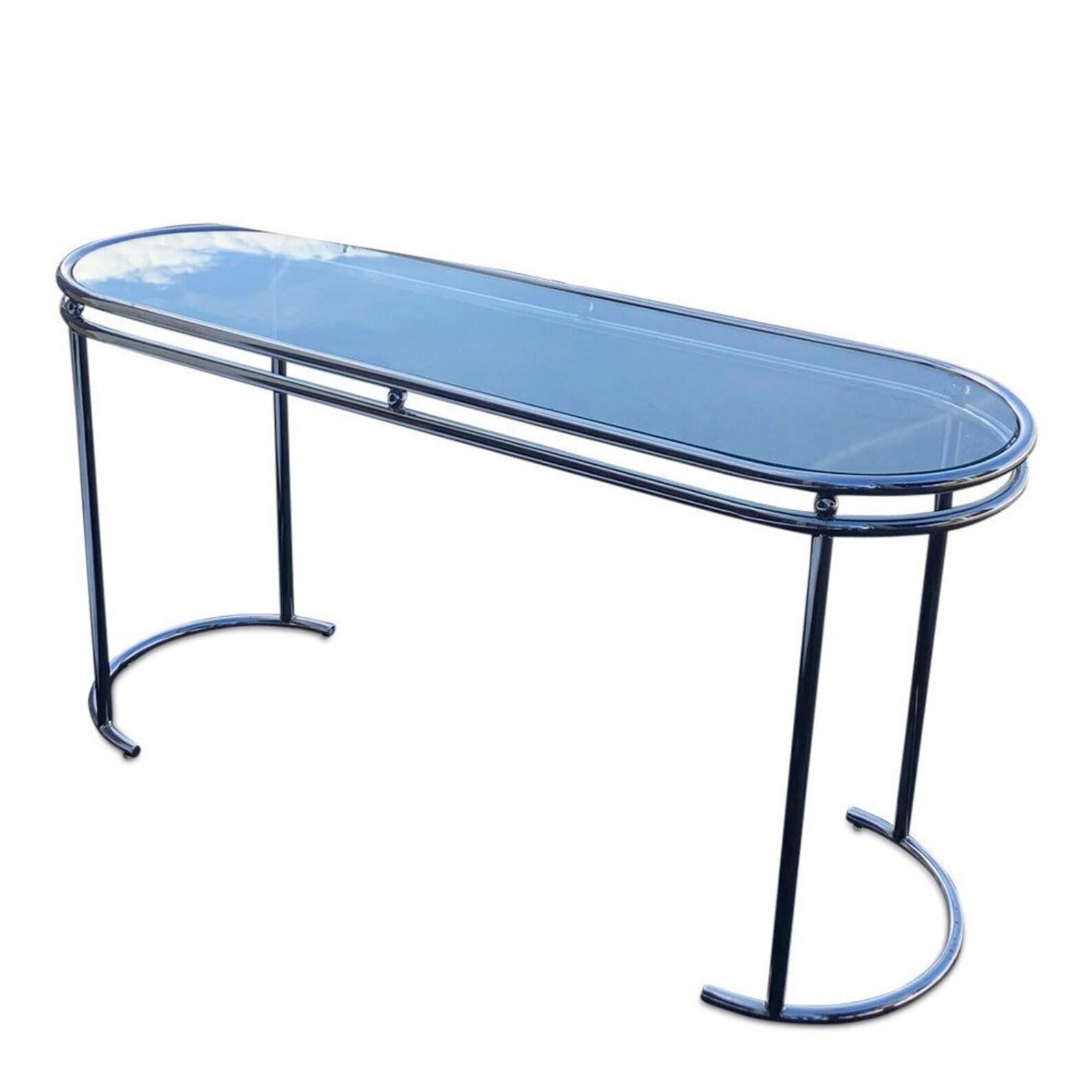 Sleek and sculptural, this vintage postmodern console table features a polished chrome frame with curved demi-lune legs and a clear glass top. The oval silhouette and airy design make it a striking yet versatile piece - perfect for entryways, living