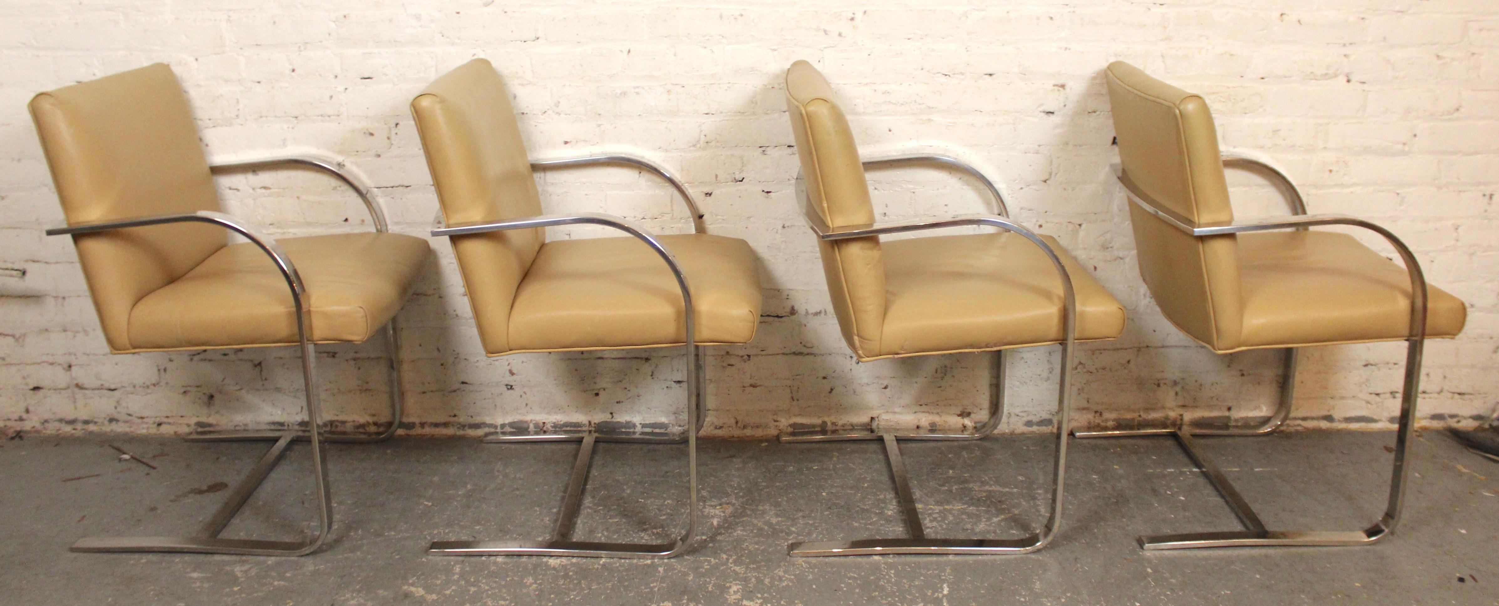 This mid-century dining set comes complete with four Brno style armchairs and a square chrome table with thick glass top. The cantilever base chairs feature wrap around chrome arms that follow through down the legs. The polished chrome finish is