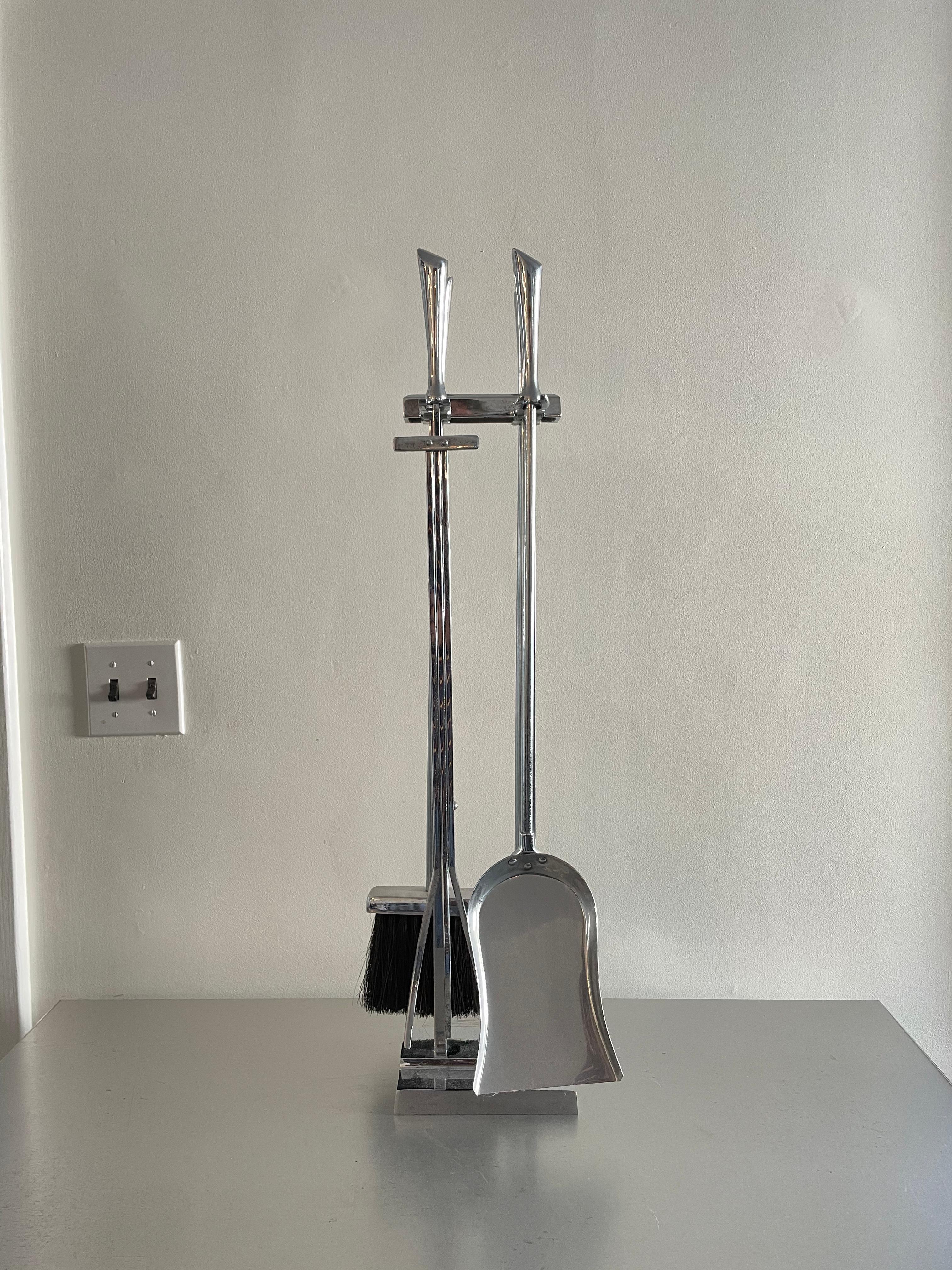 Mid-century chrome fireplace tools. Sleek handled tools rest in a modern streamline tool stand.