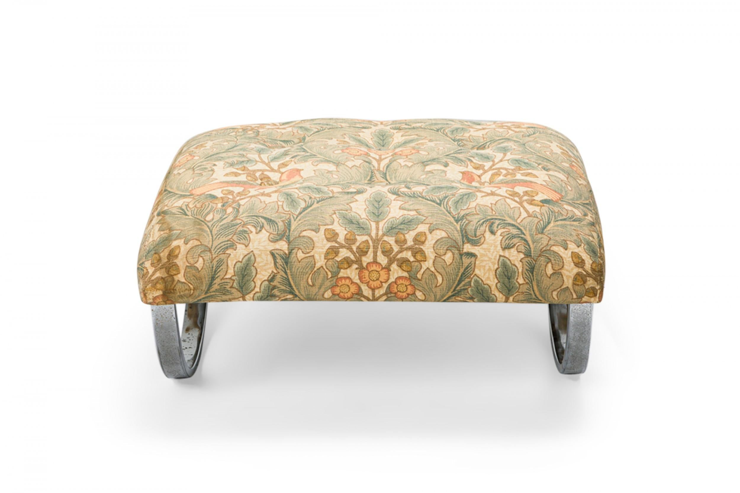 Mid-century square rocking ottoman with a bird and foliage beige, blue, and pink upholstered top cushion supported by a curved square chrome frame.
 