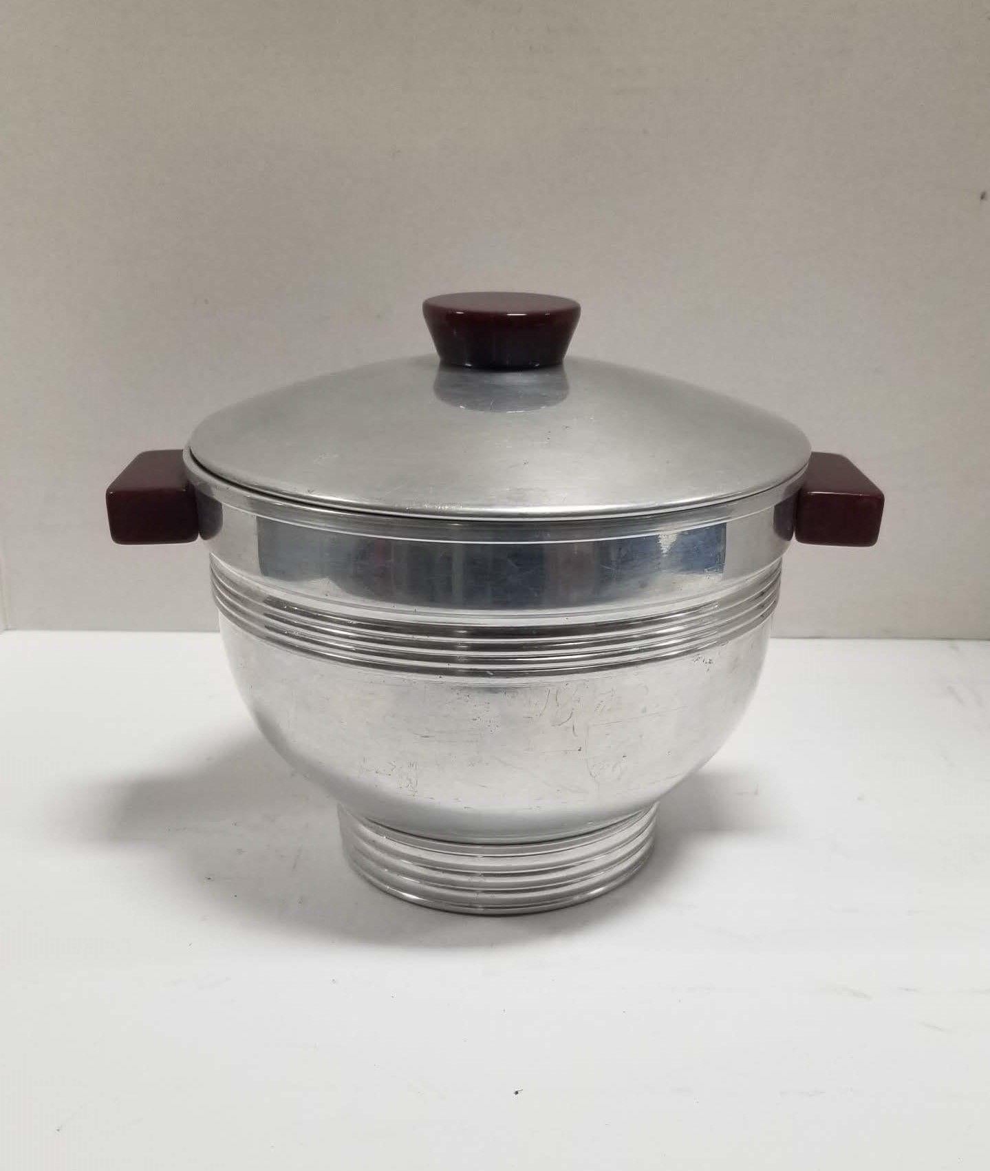 Midcentury era chromed ice bucket with Bakelite handles and lid top.
This midcentury chromed steel ice bucket is a stylish addition to any home bar. The Bakelite handles provide a comfortable grip and a touch of contrasting color to the otherwise