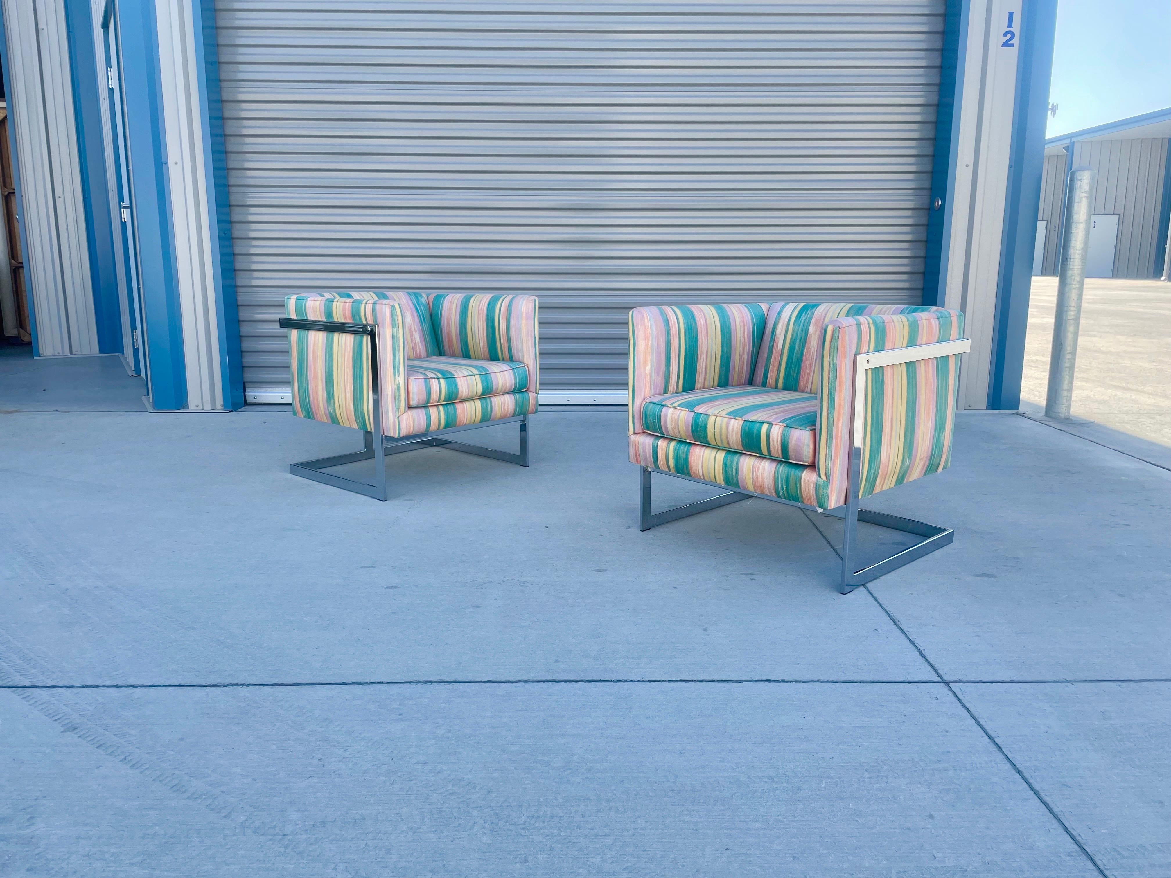Midcentury lounge chairs were designed by Milo Baughman for Thayer Coggin. These vintage cube chairs feature a beautiful T-shape chrome base design adding sturdiness and a mid-century style. They also come with pink and green patterns upholstery,