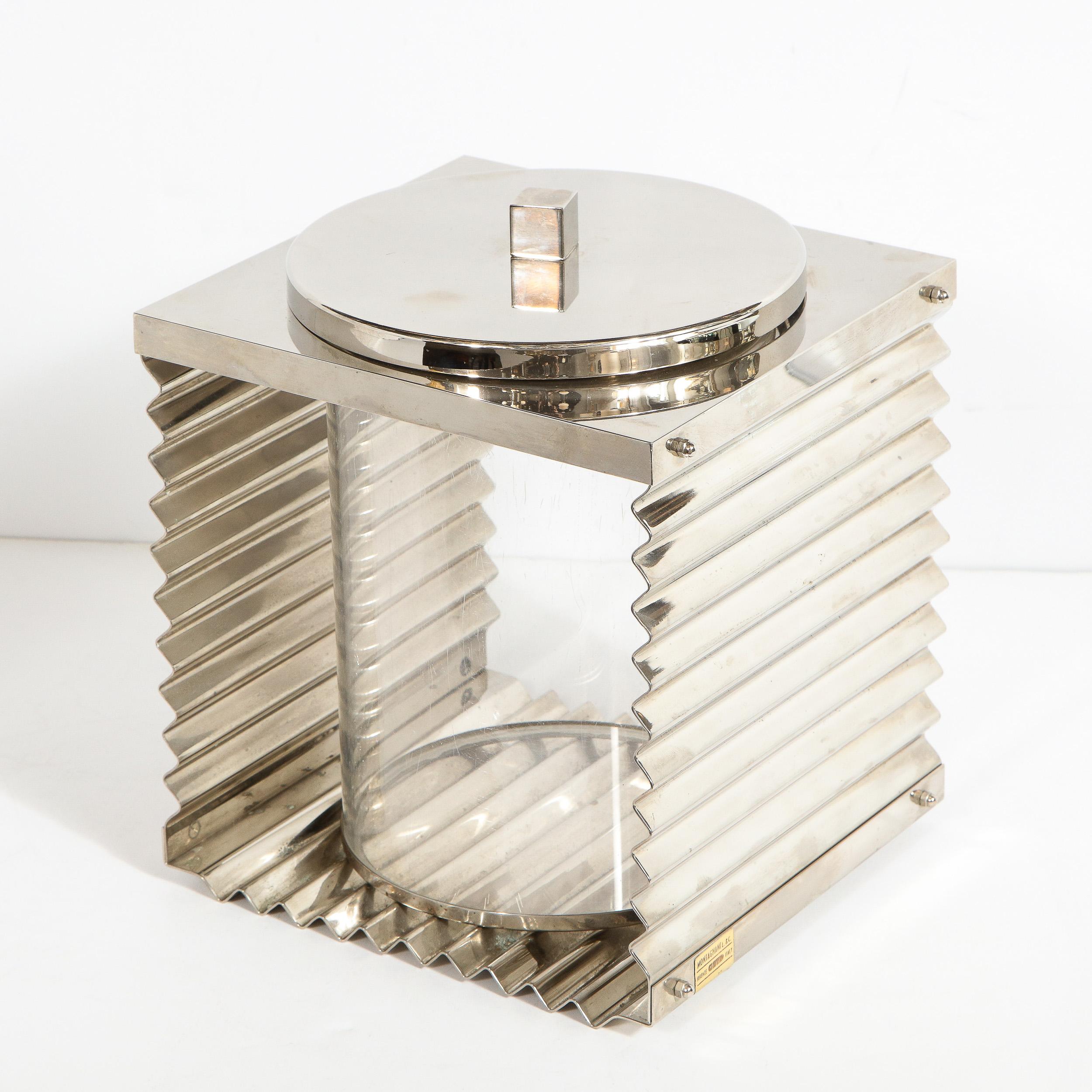 This elegant and graphic Mid-Century Modern ice bucket was realized by the esteemed maker Montagnani, in Florence, Italy, circa 1970. It features a cylindrical Lucite iceholder in the center flanked by sheets of corrugated chrome metal on two sides