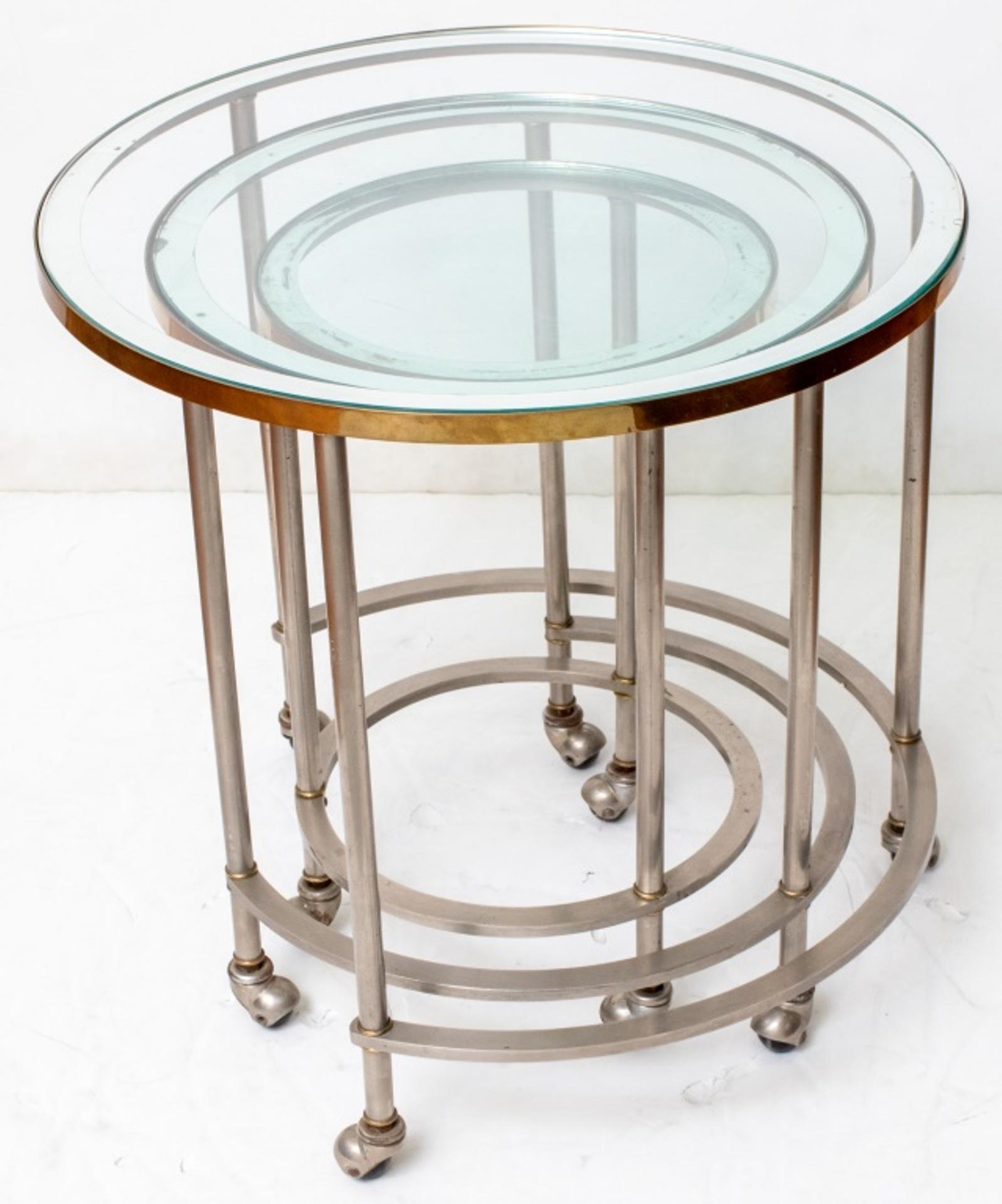 Trois tables gigognes chromées du milieu du siècle avec des plateaux en verre, toutes sur roulettes. 
Dimensions : 22.25