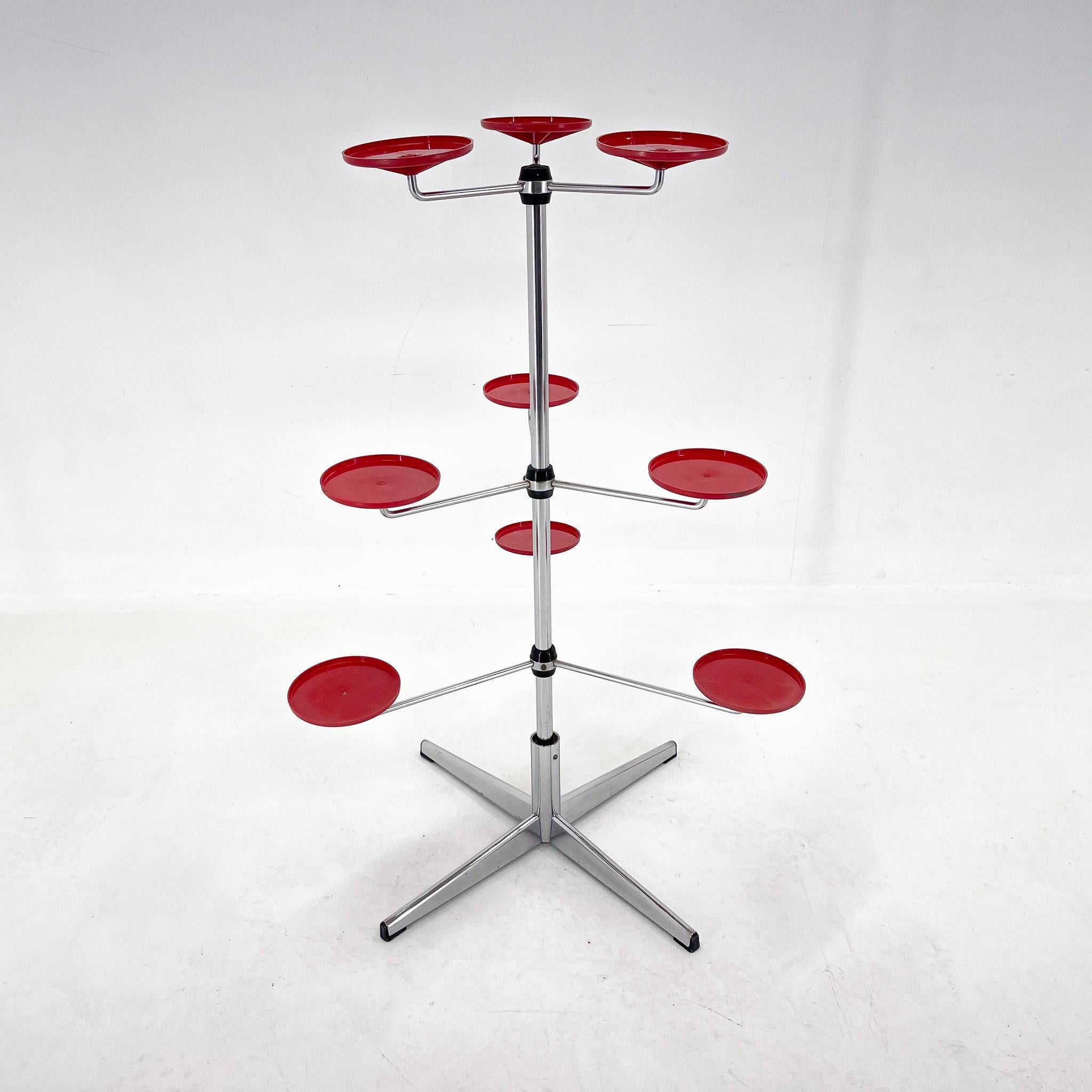 Unusual vintage plant stand made of chrome-plated metal. The stand has three tiers that can be rotated. Each tier has three red plastic trays for placing pots. The stand can of course be used to display any items or used as a stand-alone decoration.