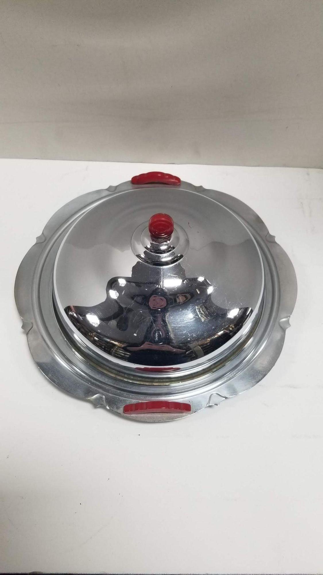 Midcentury era chromed steel serving tray with red handles and lid top
This midcentury serving tray exudes elegance and sophistication. The gleaming surface adds a touch of luxury to any occasion. Whether you're entertaining guests or simply