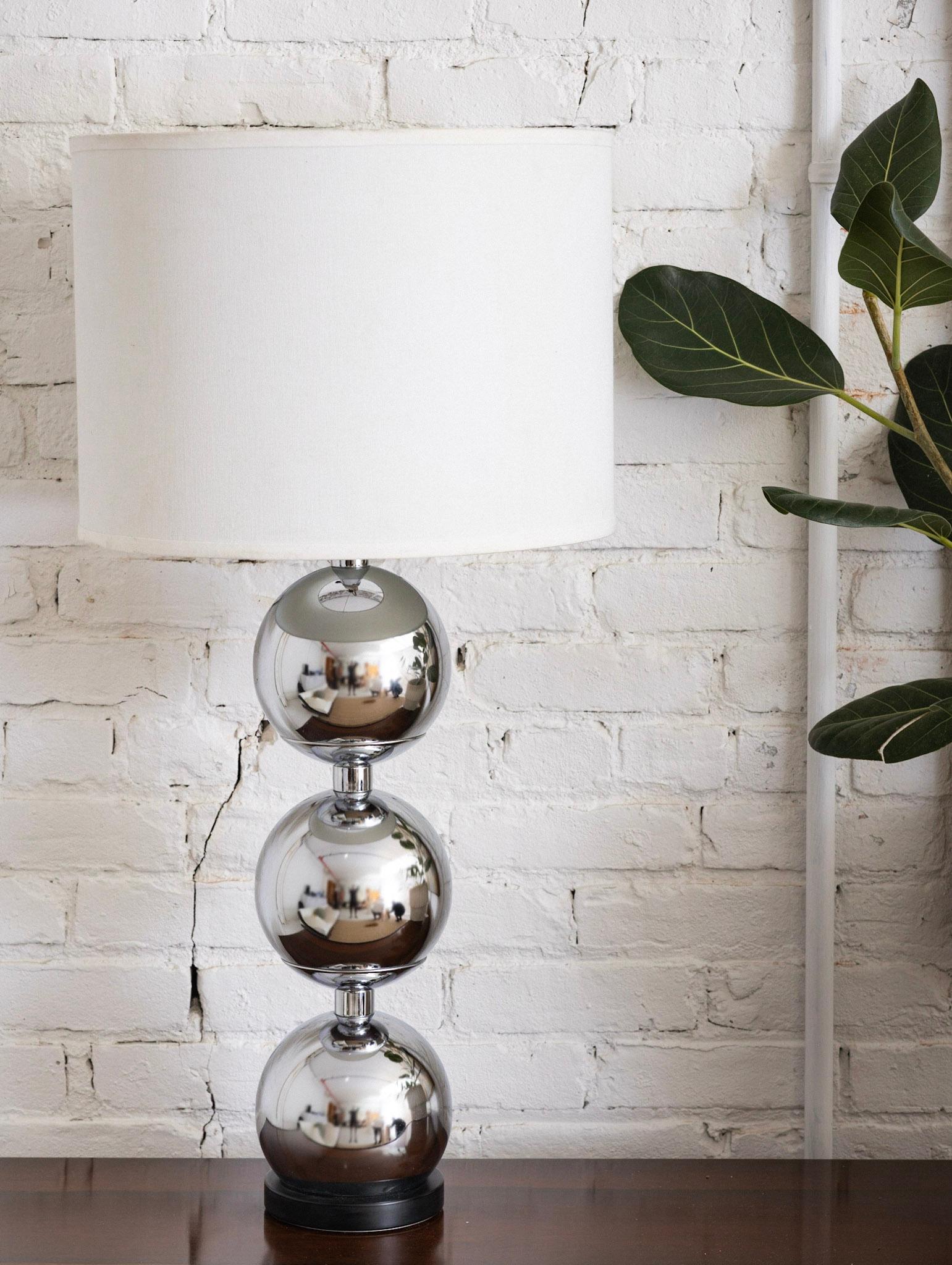 Mid-Century Modern chrome table lamp. Triple stacked sphere Silhouette. Black round plinth base. Harp and finial included. Shade NOT included. Measured from base to top of finial.