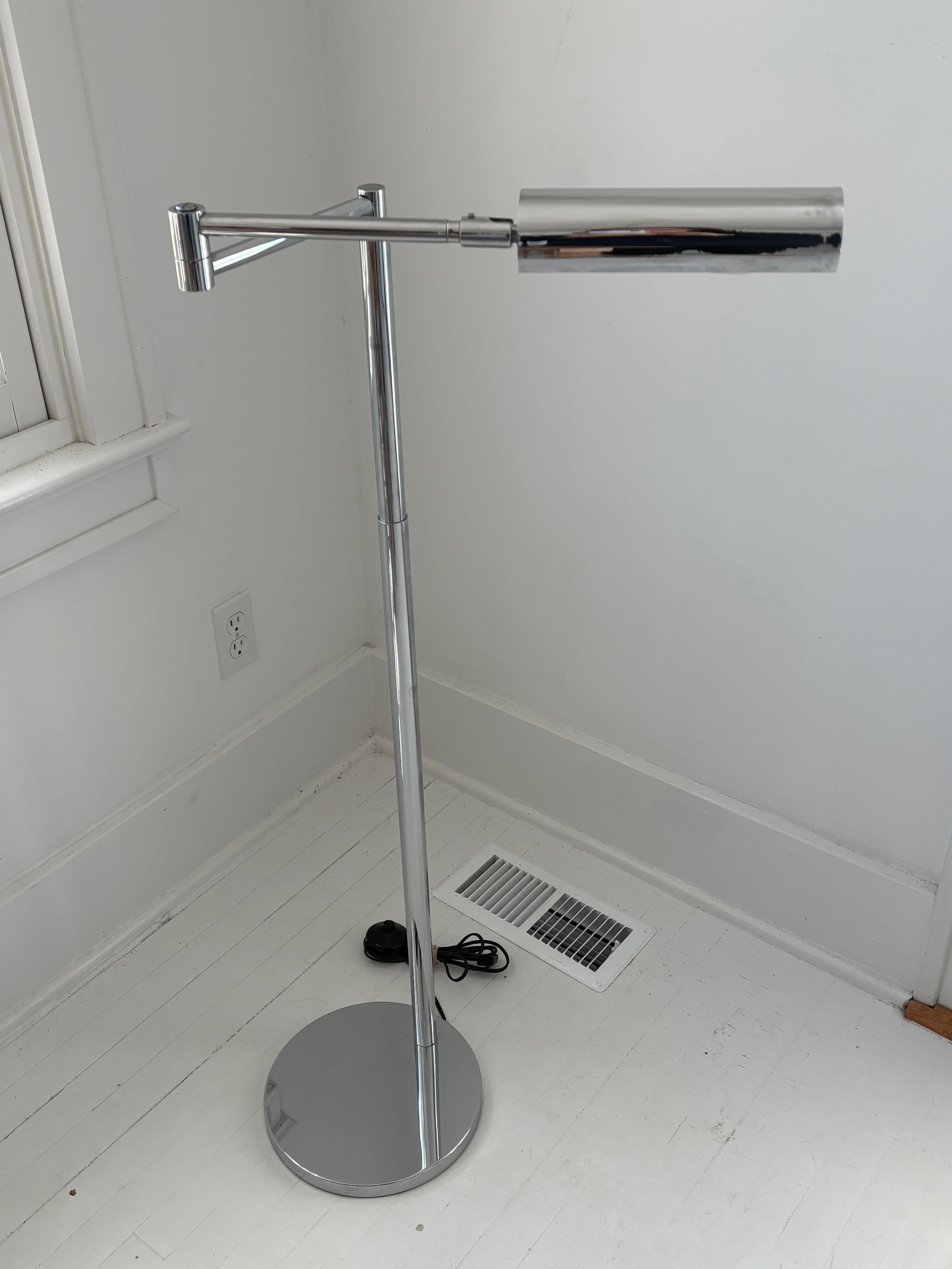 Lampada da terra a braccio oscillante cromata molto bella. Il braccio ruota e si sposta in diverse direzioni con estrema facilità e il lungo paralume cromato rotondo si muove su e giù. L'attacco per la lampadina è in porcellana e