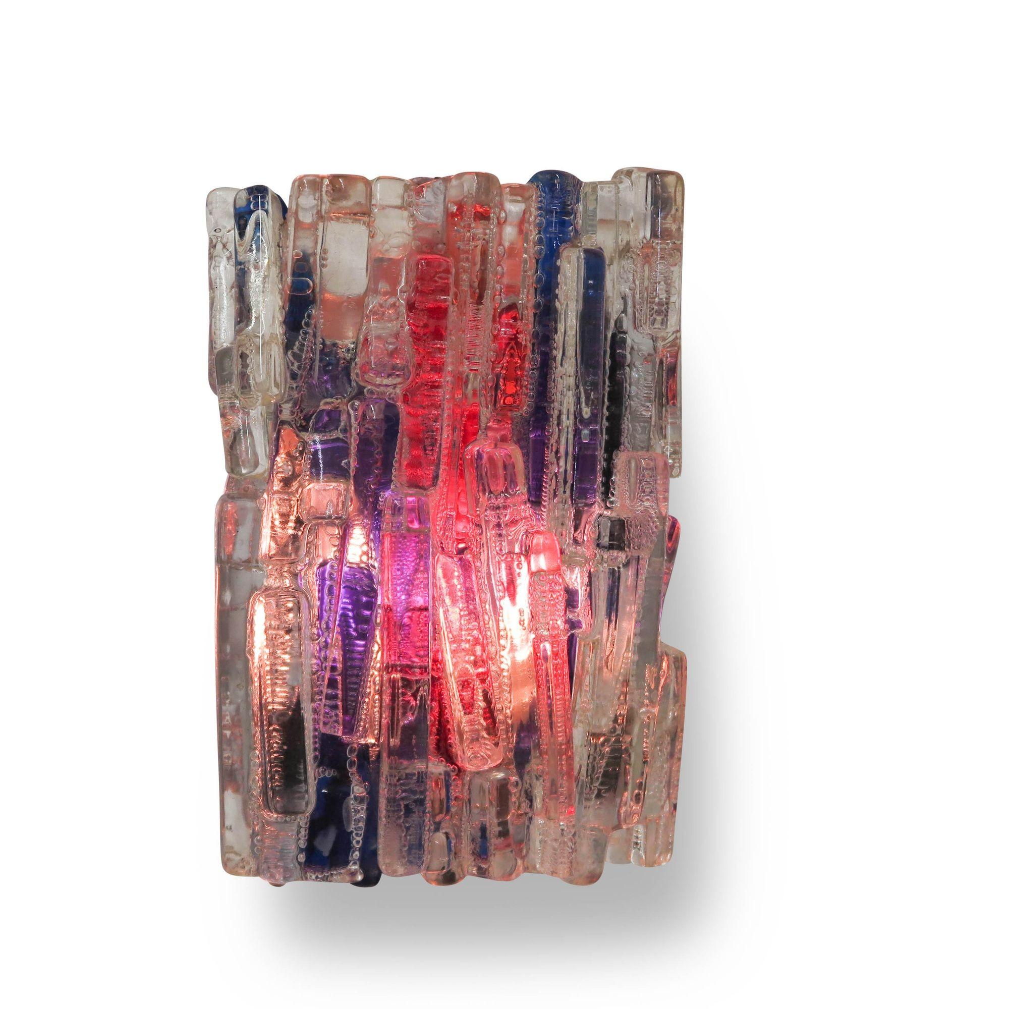 An innovative design for its era, this Mid-Century wall light from the 1970s was designed by Claus Bolby for CeBo Industri. Crafted from clear acrylic resin infused with blue and red hues, it features a textured surface that adds depth and visual