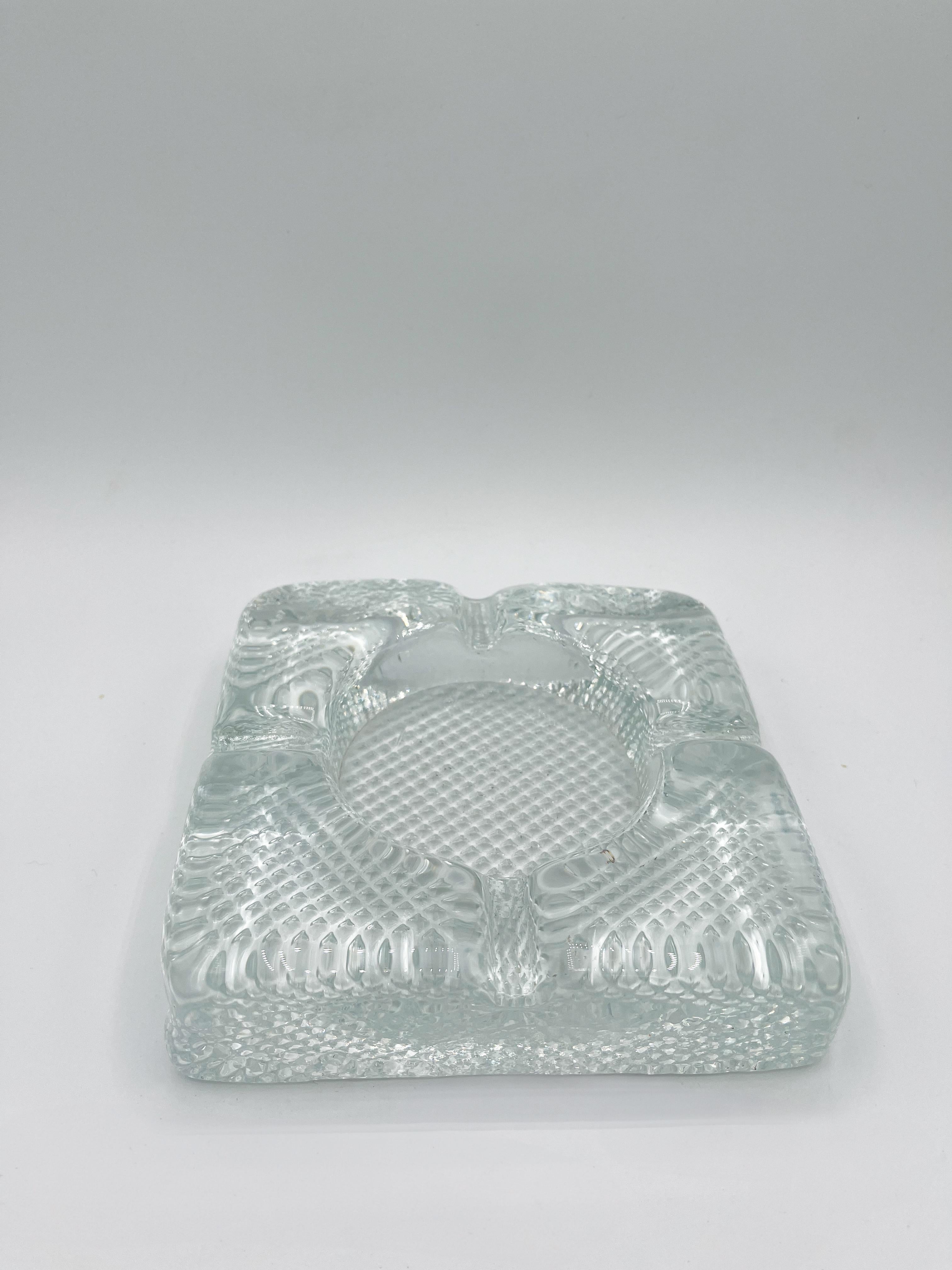 Este cenicero de cristal transparente de mediados de siglo, de la década de 1960, es una sorprendente mezcla de diseño minimalista y elegancia atemporal. Fabricado con cristal grueso de alta calidad, su estética clara y versátil lo hace adecuado