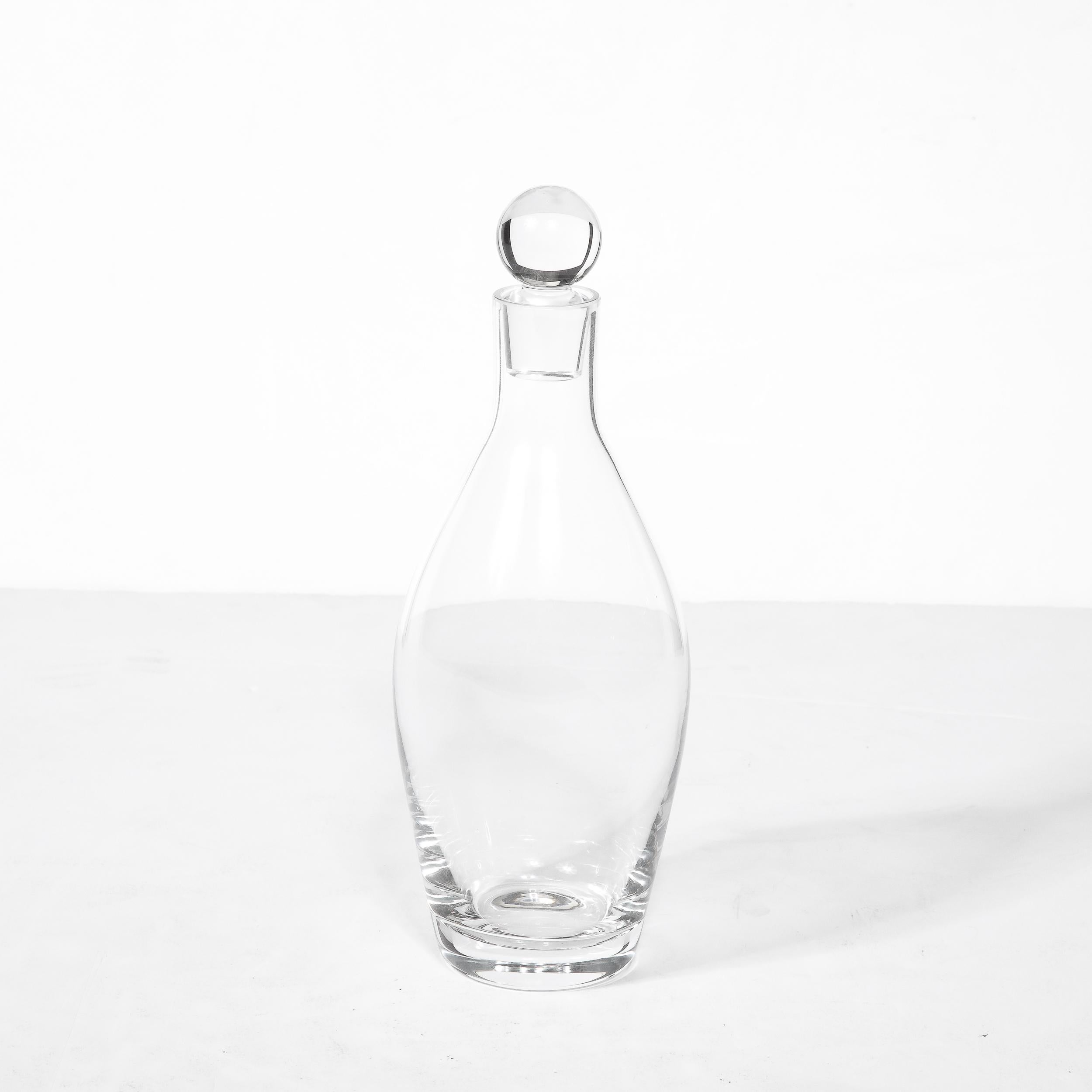 This elegant and minimal decanter in transparent glass originates from Germany during the 20th Century signed Eugene Von Boch for Villeroy and Boch. The body of the piece is well balanced and features a lovely spherical stopper that seamlessly fits