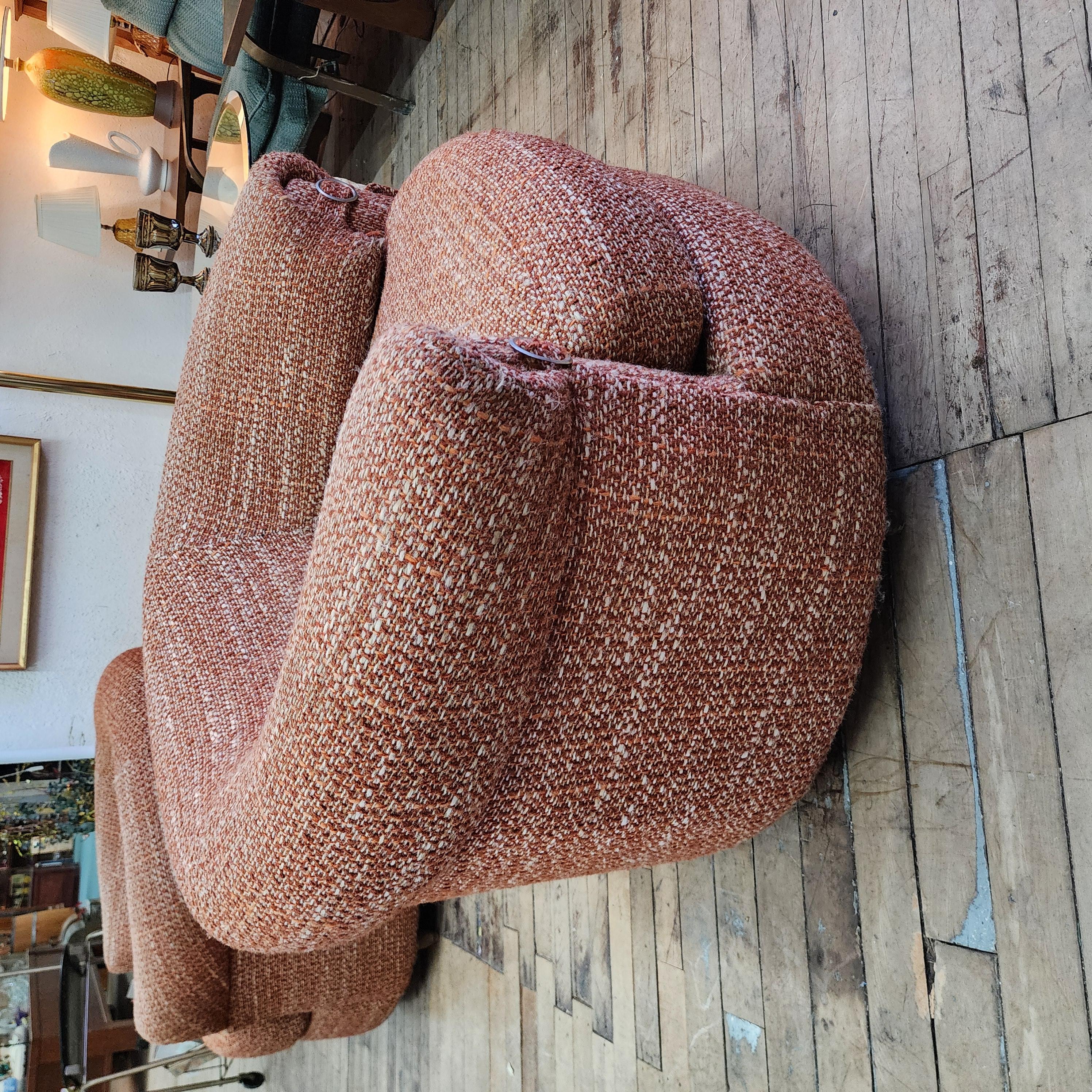 This is a unique pair of club chairs that have a great mid-century or 1970s vibe. They are low and large with a burnt orangish red color. The fabric is like a tweed. The the foam is very comfortable and squishy. You sink into these in a great way.