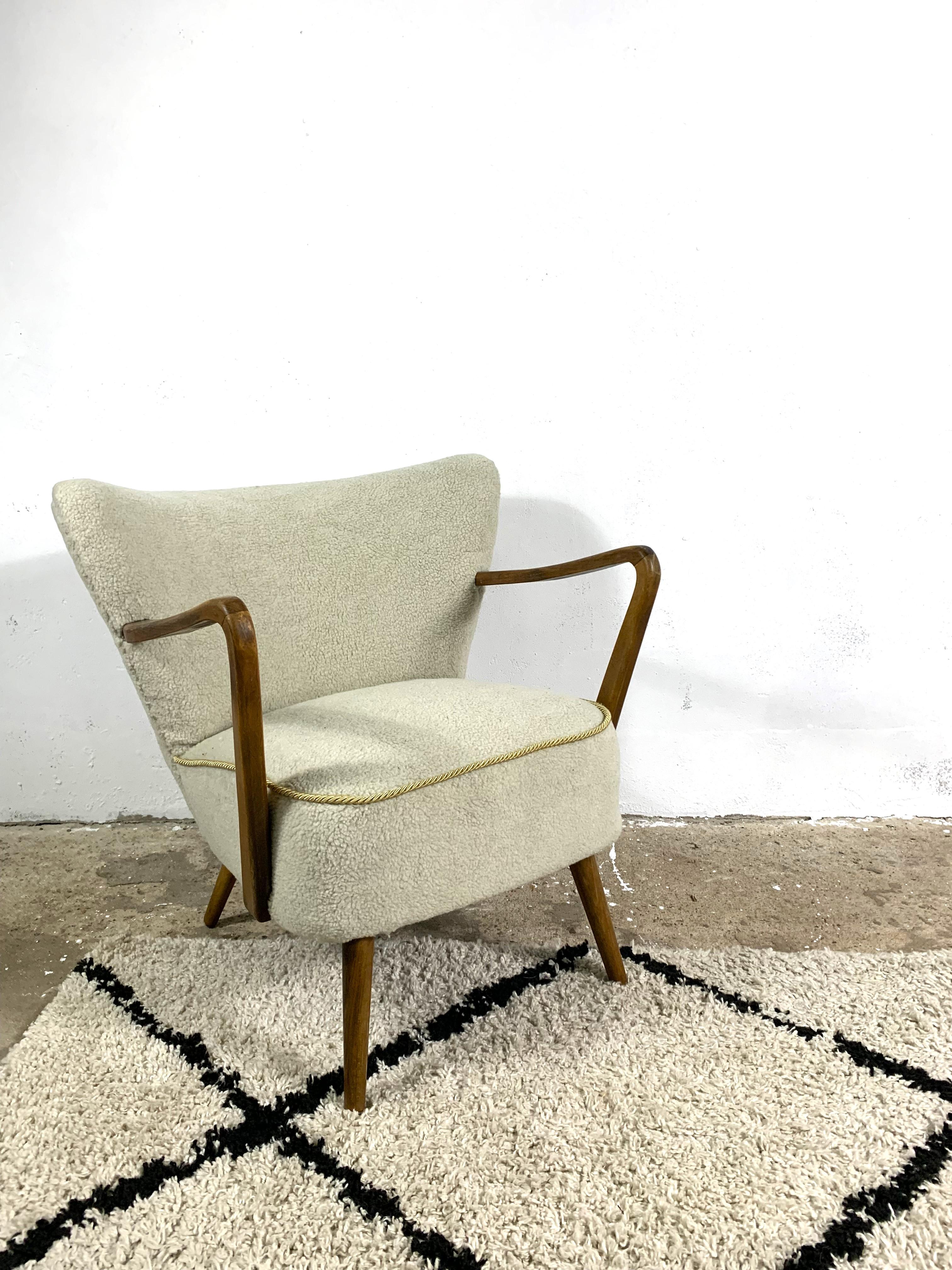 Cocktail chair with wooden armrests, original from the 1950s. Replaced filling, new upholstery made of soft boucle fabric. Stylish, comfortable piece of furniture.