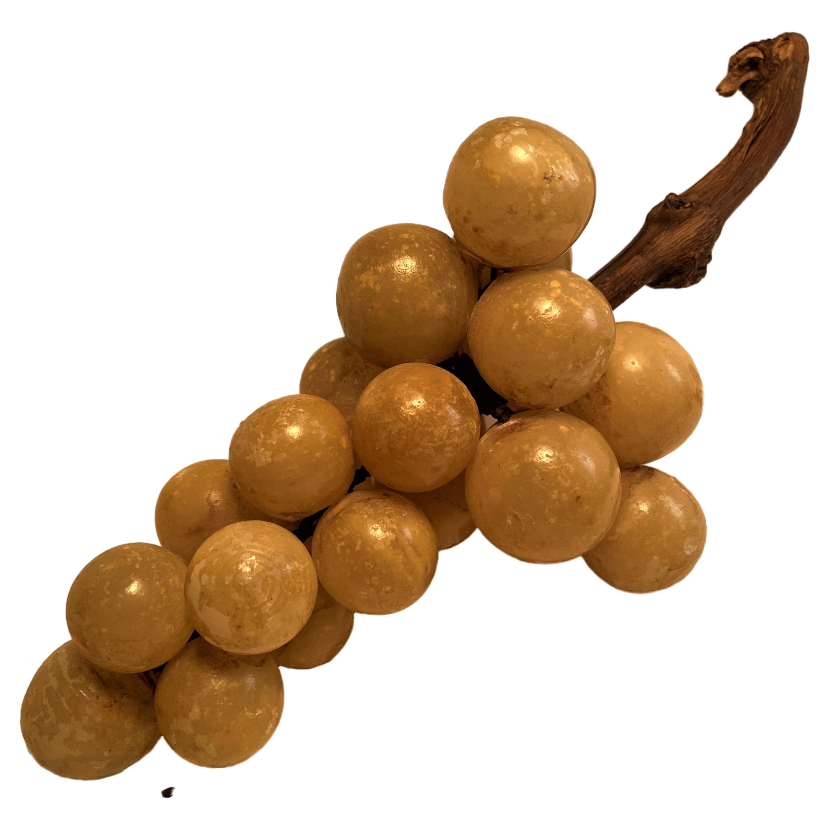 This is a fun, decorative bunch of alabaster grapes which have a shiny finish on them, the finish has aged and has worn off of some grapes and is pitted or chipped on others. The effect gives the grapes an interesting and appealing look. They are
