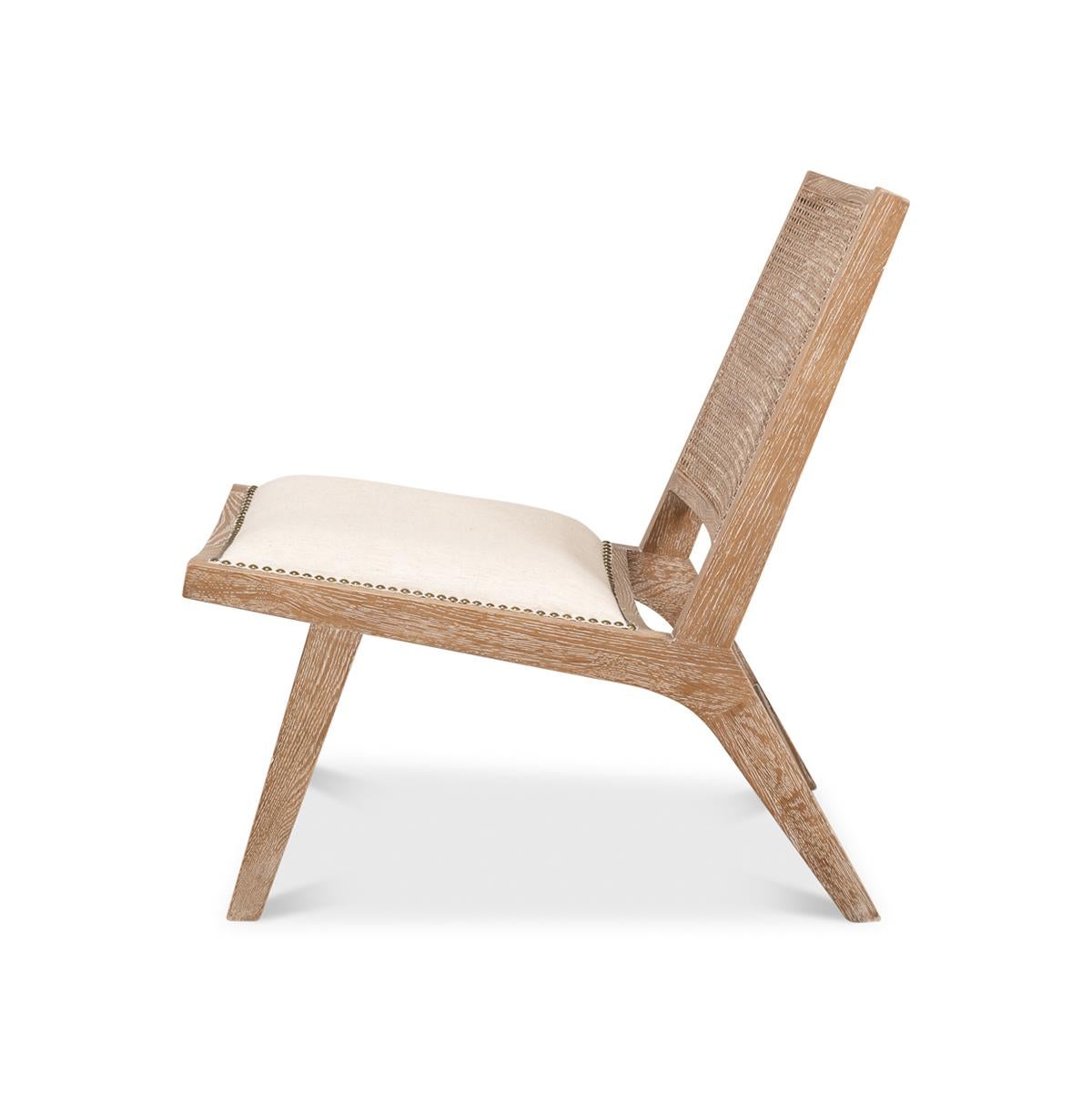 A low-slung side chair. With a natural lightly whitewashed frame, an inset caned backrest and an off-white linen upholstered seat.

 Dimensions: 22