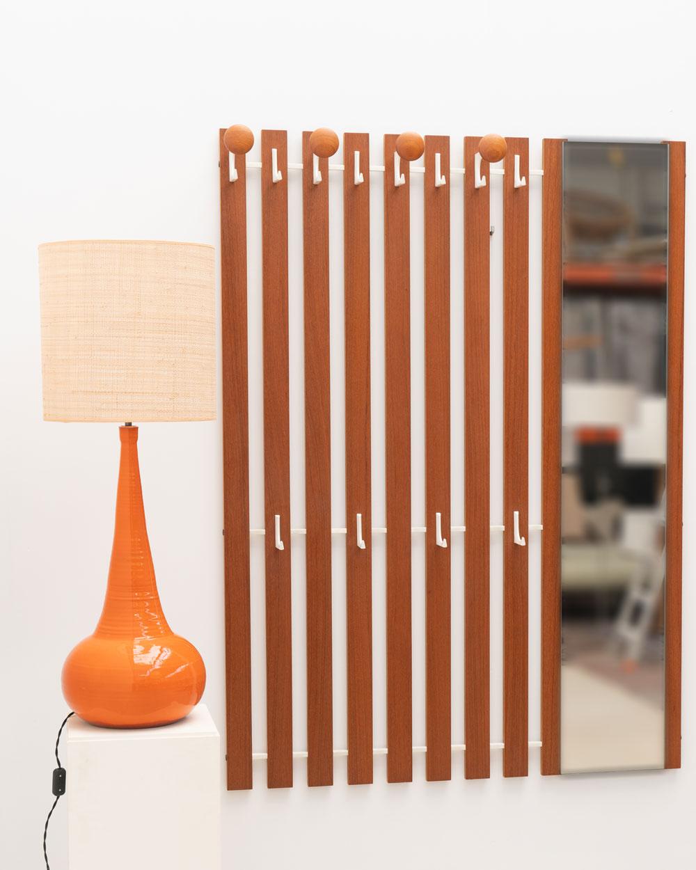 This wall coat rack from 1960s Germany combines teak wood and aluminum, with an integrated mirror. The teak frame is combined with white aluminum hooks, offering both functionality and a nod to Mid-Century Modern design. This piece offers a