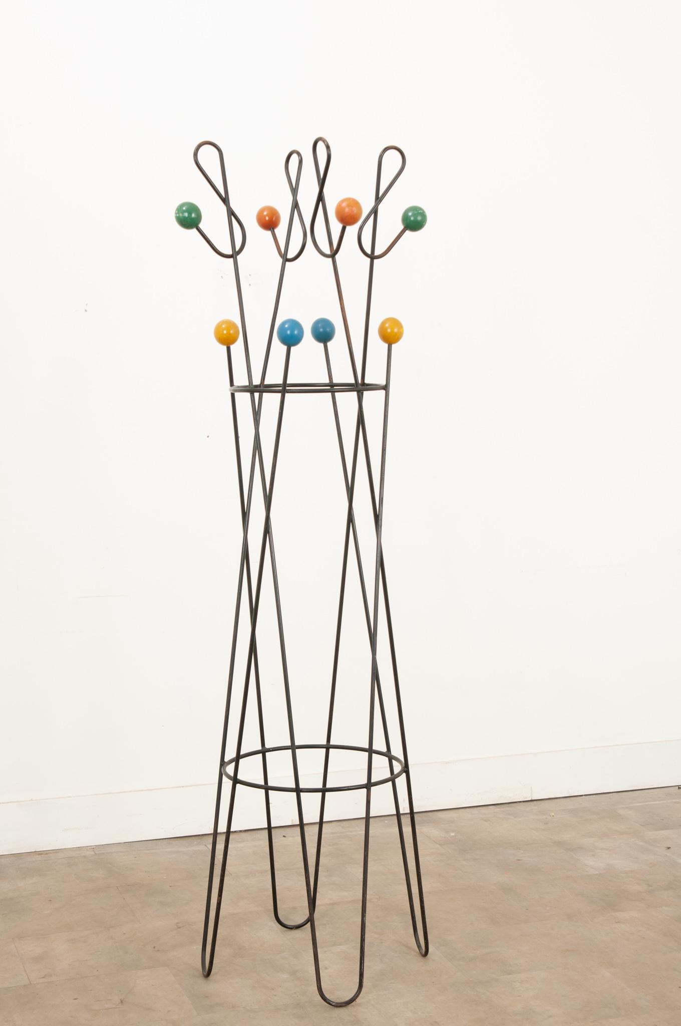 A whimsical free standing iron coat stand by Roger Feraud from the 1950s. This design classic is constructed from lacquered black metal with eight wooden colored balls. Well designed, in good vintage condition, and very stable due to its weight. A