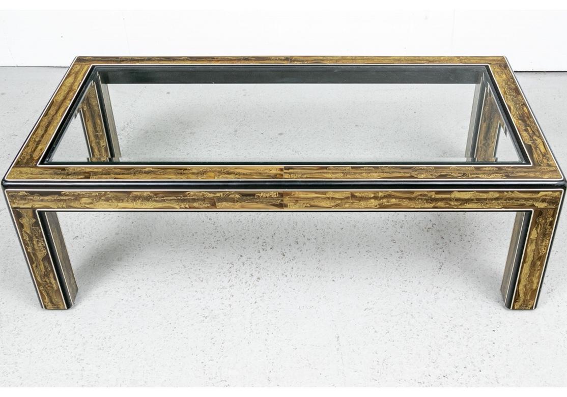 Classic Mid Century design by Bernhard Rohne and made by Mastercraft. The long rectangular table frame with acid etched brass bands in abstract shaped and curved motifs, many with wheels. In a golden tone on variegated back grounds. The bands set